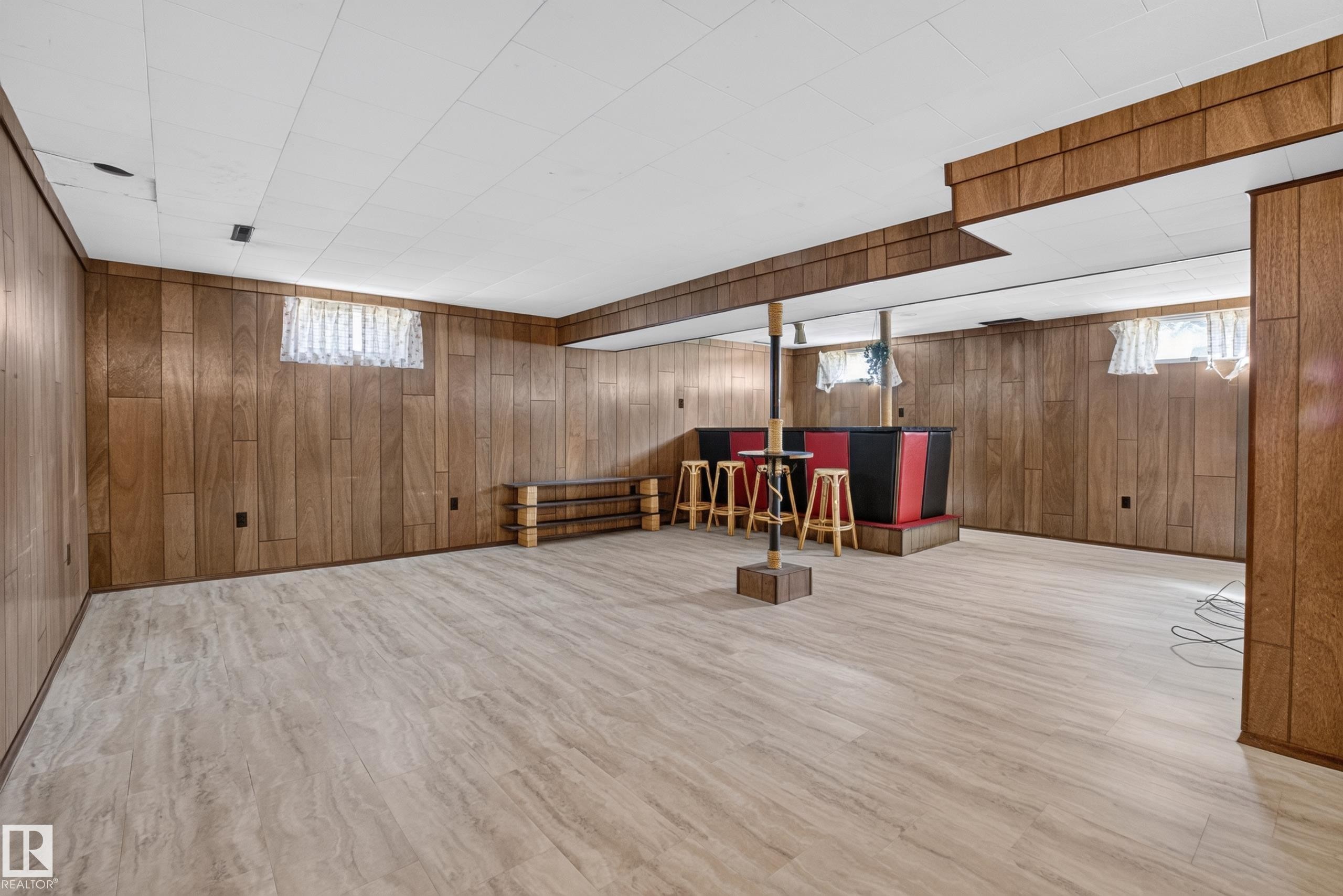Finished lower level with wood-finish paneling, drop ceiling, and light-toned flooring - 16009 93A Avenue Nw, Edmonton, AB - Indoor