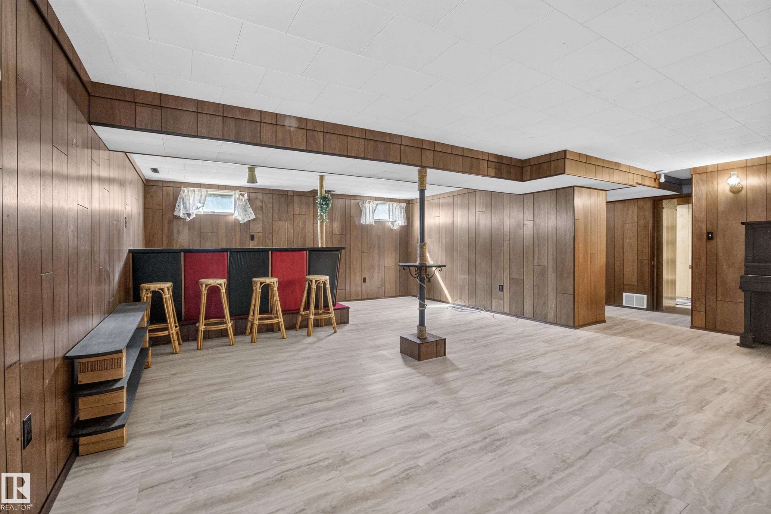 Lower level featuring wood-finish wall paneling, a built-in bar, and light-toned flooring - 16009 93A Avenue Nw, Edmonton, AB - Indoor
