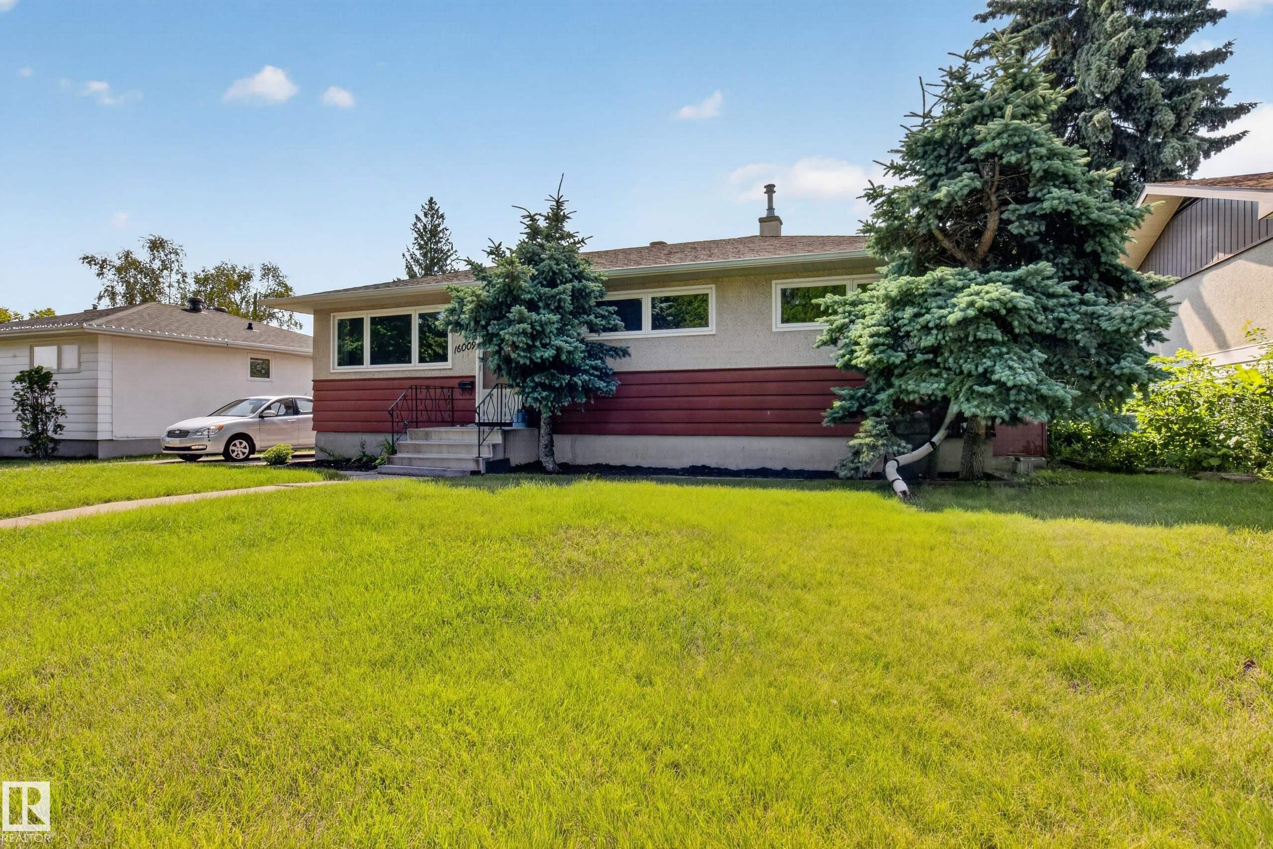 Front exterior with a light stucco finish, red horizontal siding, and multiple front-facing windows - 16009 93A Avenue Nw, Edmonton, AB - Outdoor