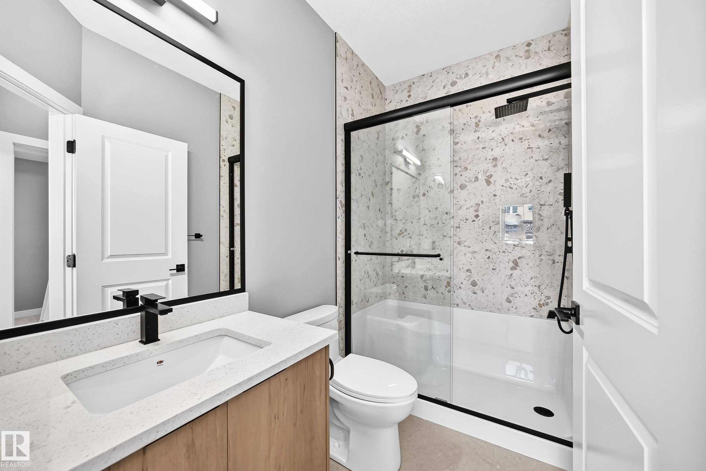Contemporary bathroom featuring a wood-finish vanity, white countertop, and black fixtures - 426 Crystal Creek Link, Leduc, AB - Indoor Photo Showing Bathroom