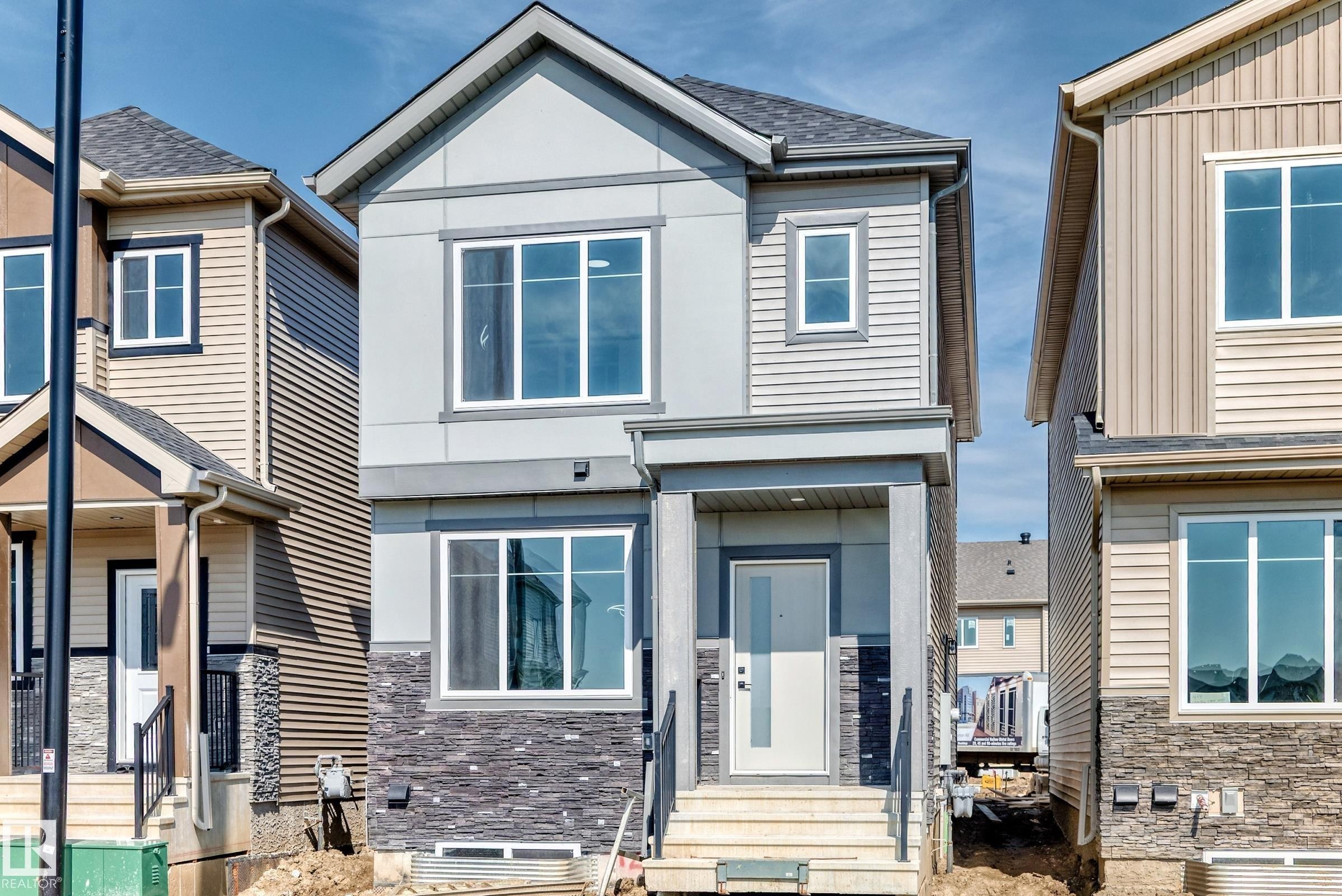 Two-story residence featuring a gabled roof, mixed exterior cladding including horizontal siding and stone veneer, and a covered front entry with railing - 426 Crystal Creek Link, Leduc, AB - Outdoor With Facade