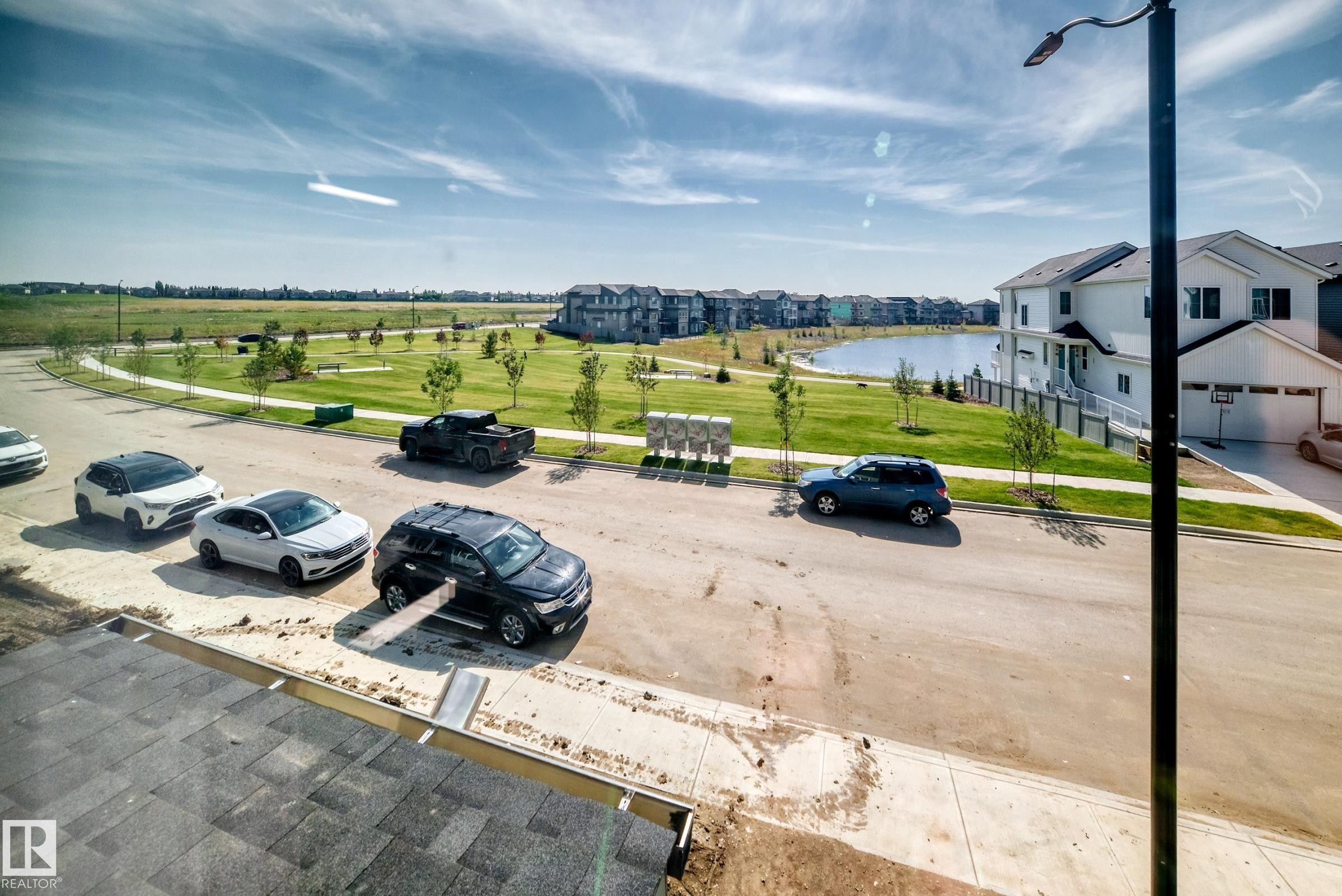 Green space with mature trees, a pond, and a paved walking path - 426 Crystal Creek Link, Leduc, AB - Outdoor With View
