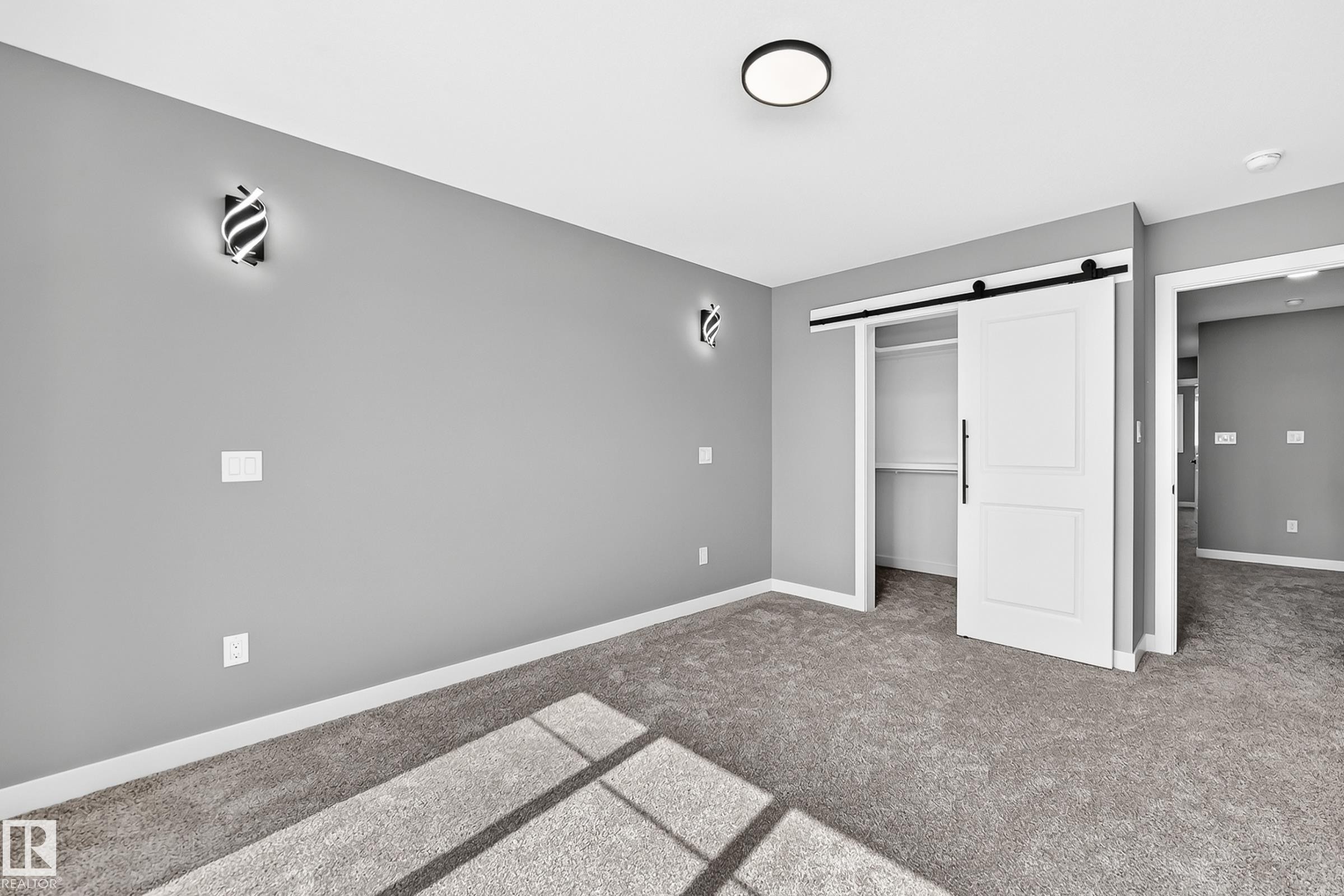 Barn door entry to closet, contemporary ceiling light fixture, wall-mounted sconces, and neutral carpeting - 426 Crystal Creek Link, Leduc, AB - Indoor Photo Showing Other Room