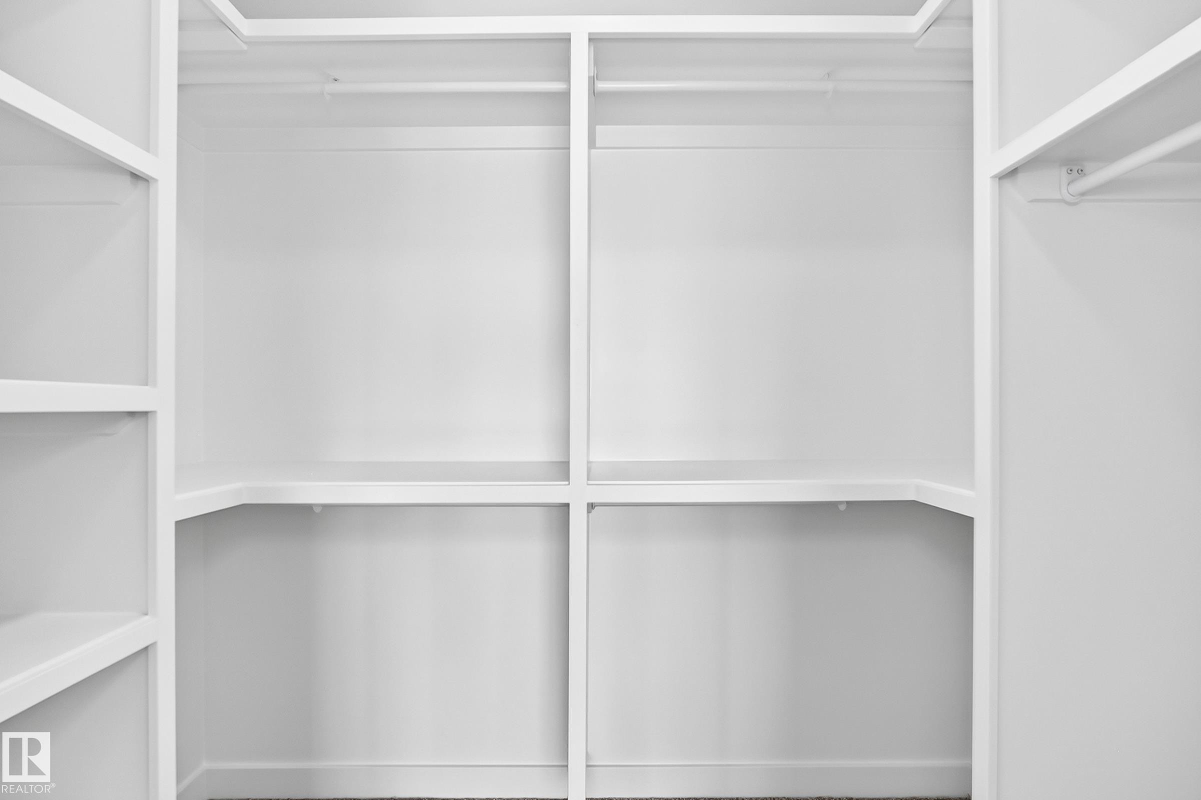 Integrated white shelving system with multiple storage levels and hanging rods - 426 Crystal Creek Link, Leduc, AB - Indoor With Storage
