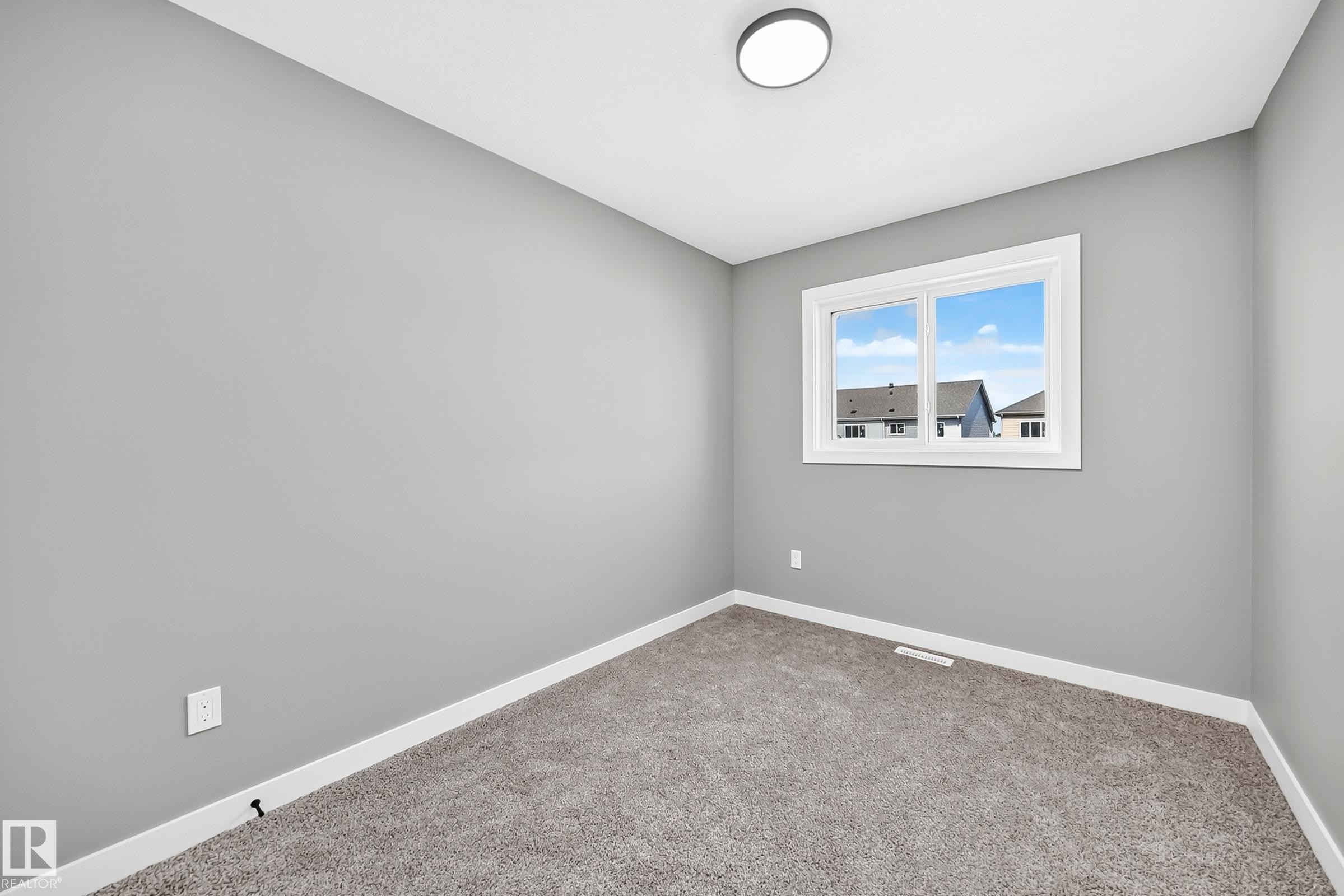 Neutral gray walls with white trim, carpeting, a white-framed window, and an overhead flush-mount light fixture - 426 Crystal Creek Link, Leduc, AB - Indoor Photo Showing Other Room