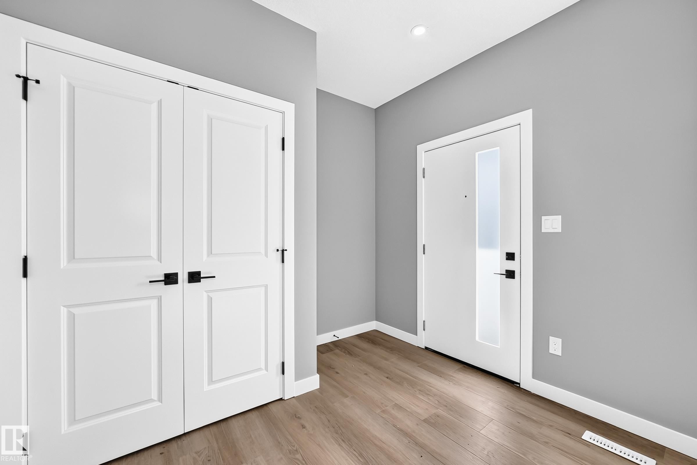 Wood-finish flooring, white paneled doors with matte black hardware, and recessed lighting - 426 Crystal Creek Link, Leduc, AB - Indoor Photo Showing Other Room