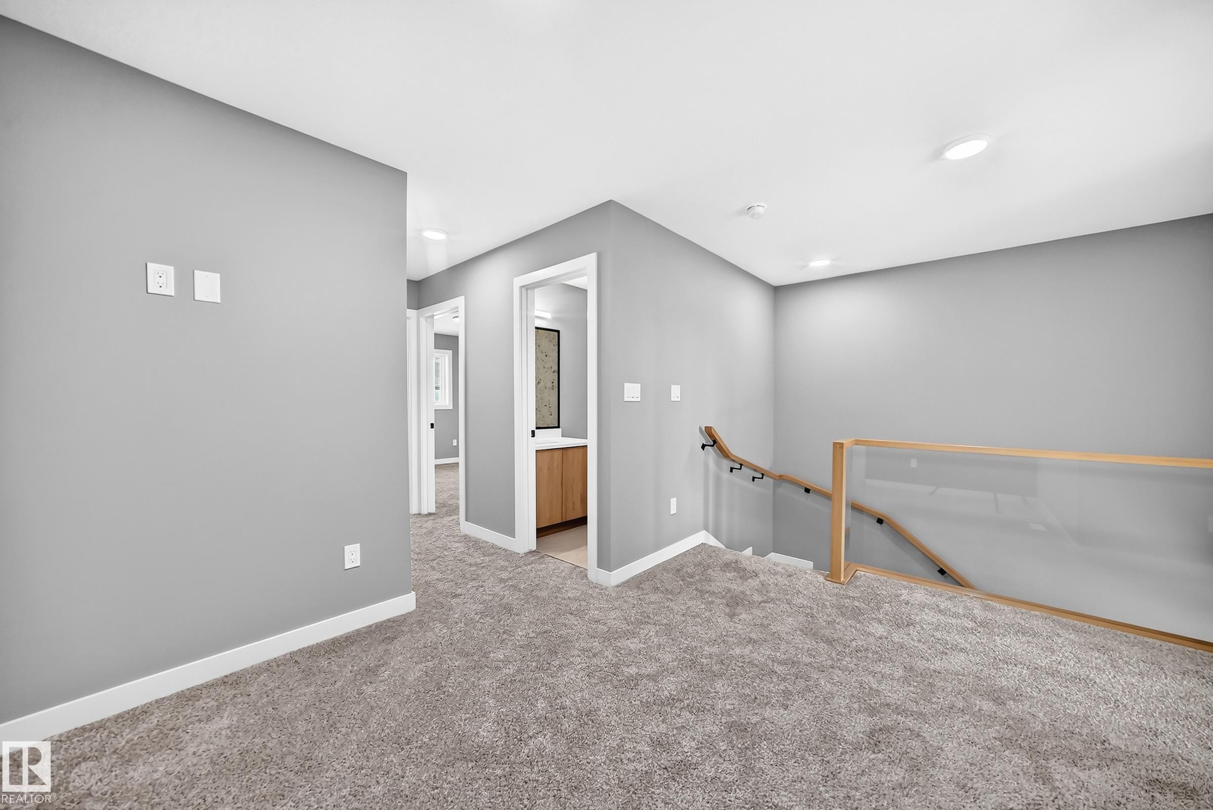 Carpeted hallway with a glass and wood-finish railing, recessed lighting, and a visible vanity with a dark countertop - 426 Crystal Creek Link, Leduc, AB - Indoor Photo Showing Other Room