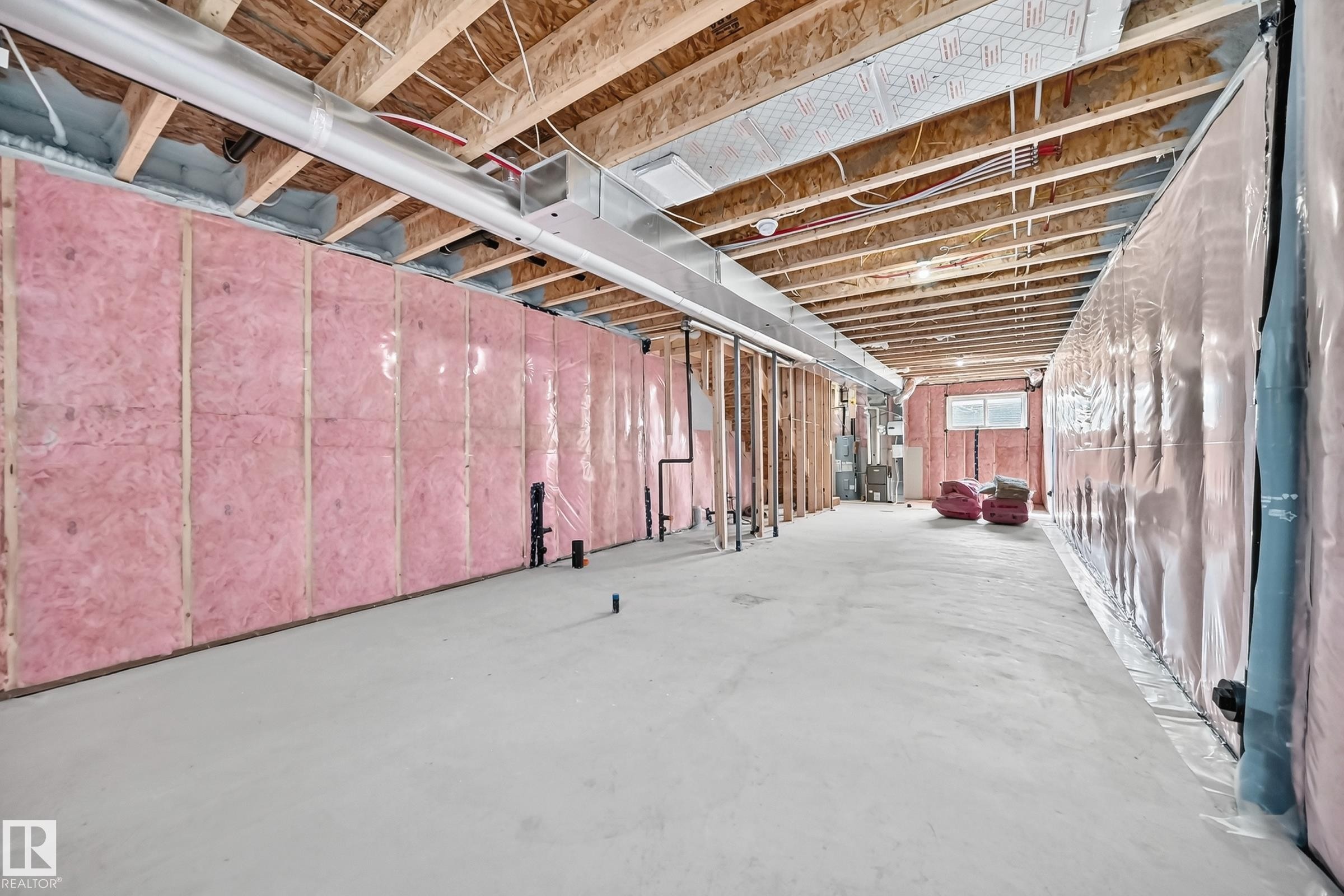 Unfinished lower level with exposed ceiling joists, pink insulation, and concrete flooring - 426 Crystal Creek Link, Leduc, AB - Indoor Photo Showing Basement