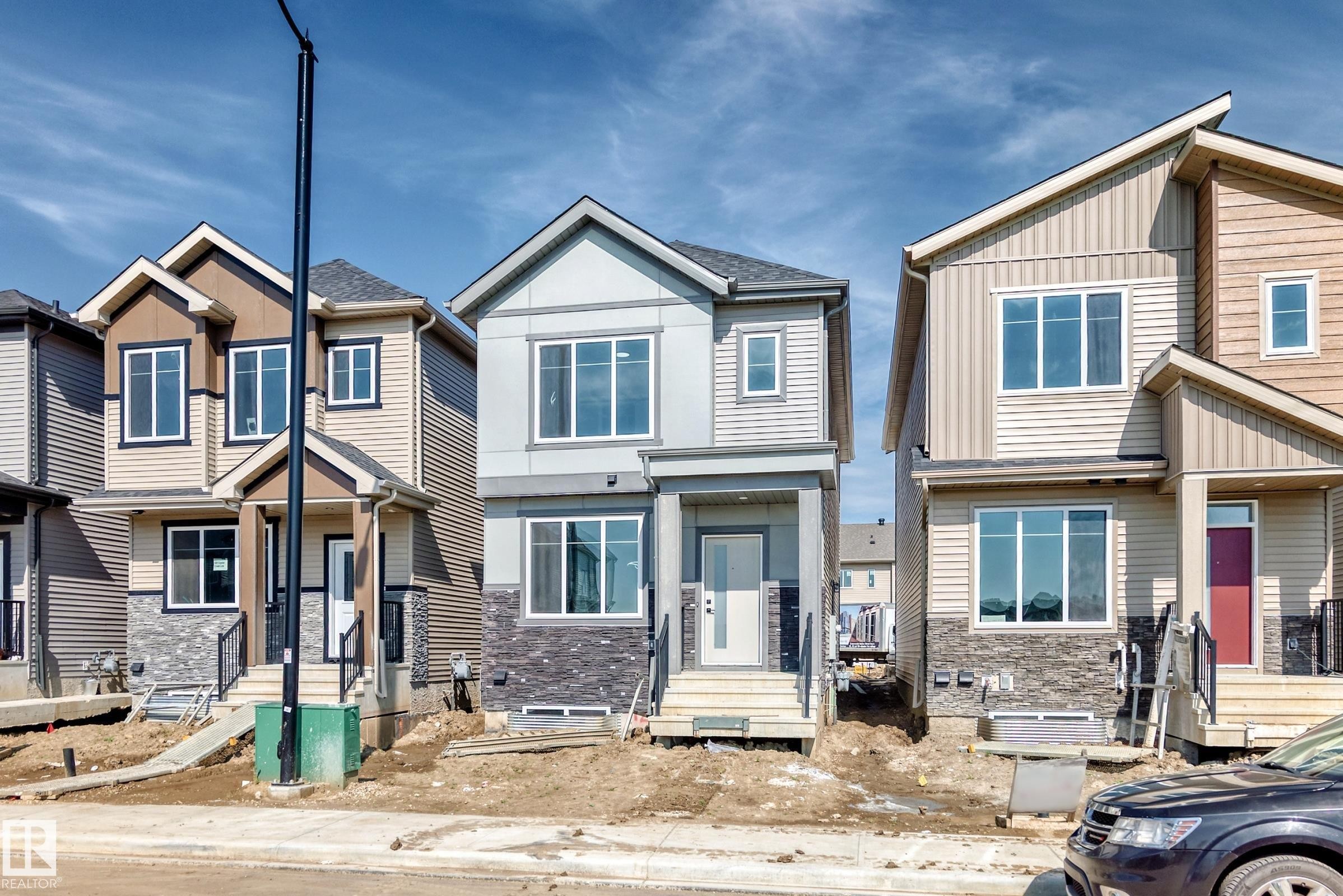 Modern two-story residence with a multi-textured exterior, featuring neutral-toned siding and stone-finish accents - 426 Crystal Creek Link, Leduc, AB - Outdoor With Facade