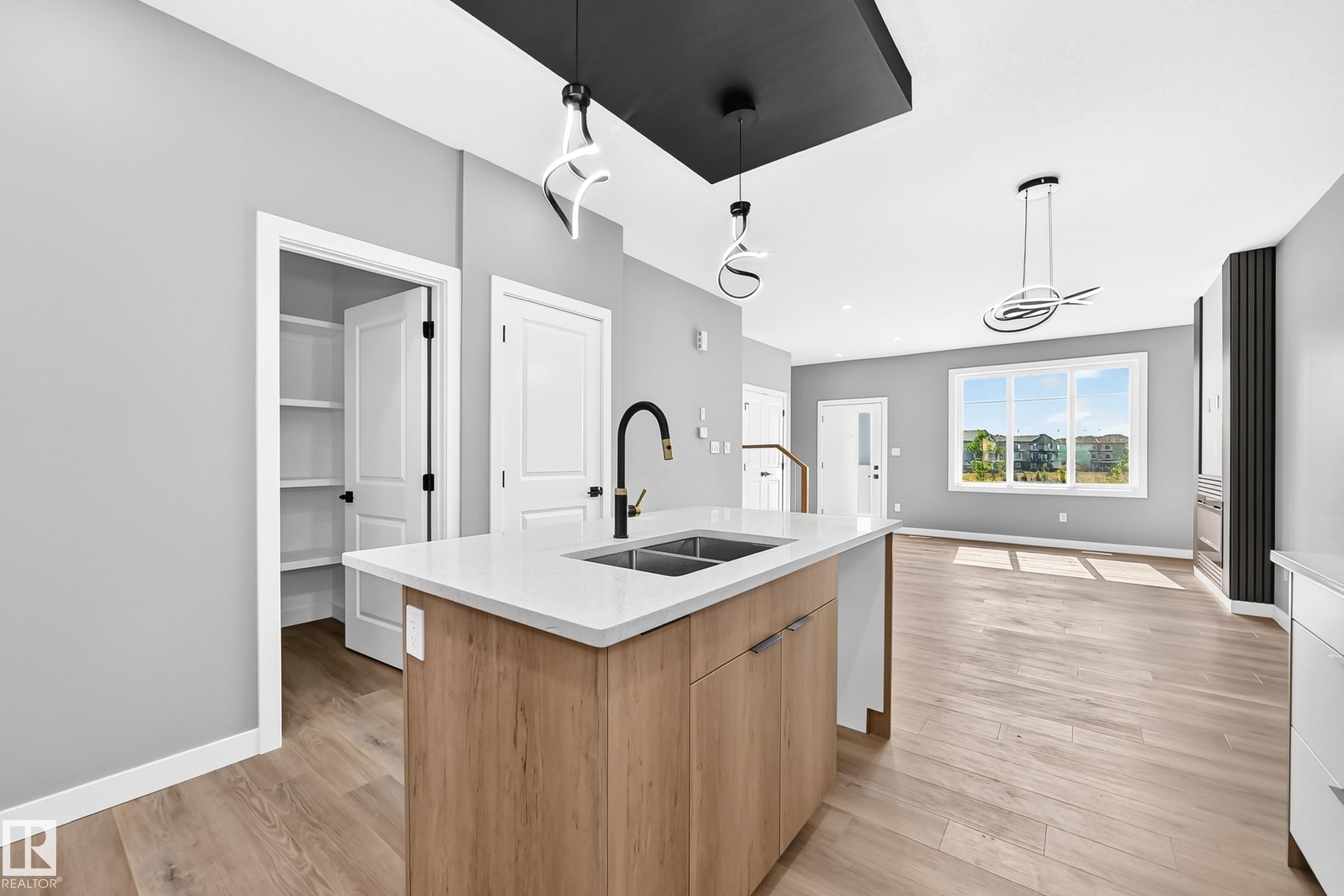 Kitchen island with a white countertop and wood-finish cabinetry - 426 Crystal Creek Link, Leduc, AB - Indoor Photo Showing Kitchen With Double Sink
