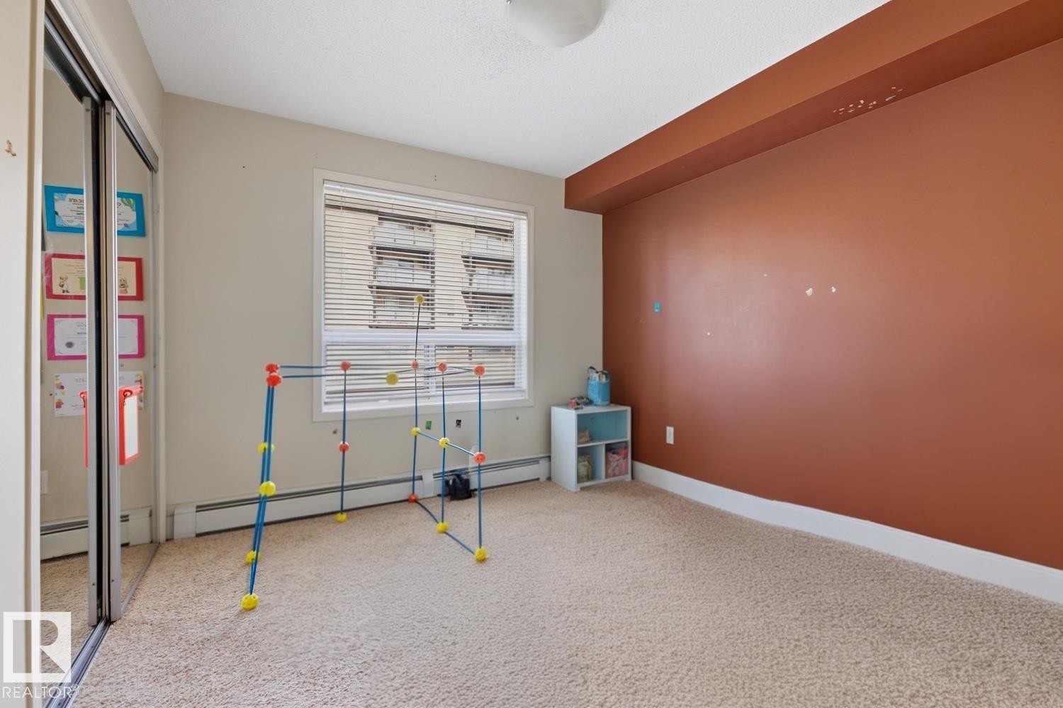 Wall-to-wall carpeting, large window with blinds, and built-in closet with mirrored sliding doors - #106 13907 136 St Nw, Edmonton, AB - Indoor