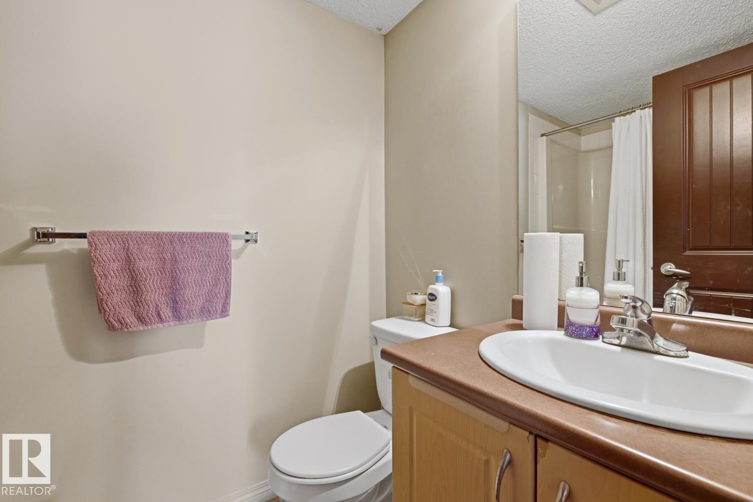 Built-in vanity with integrated sink, chrome faucet, and wood-finish cabinetry - #106 13907 136 St Nw, Edmonton, AB - Indoor Photo Showing Bathroom