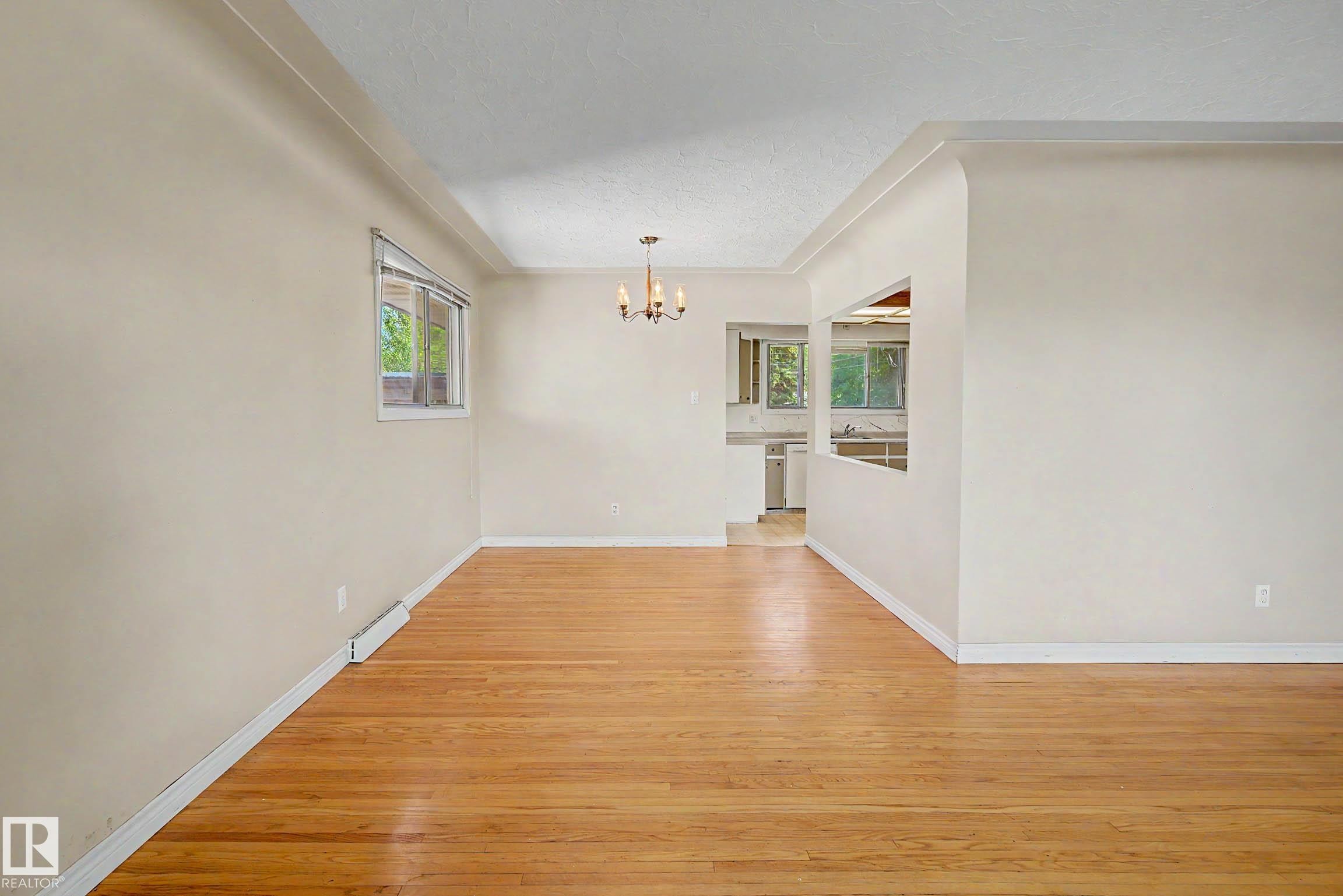 Hardwood flooring throughout, recessed ceiling, and a traditional chandelier - 9723 76 Street Nw, Edmonton, AB - Indoor Photo Showing Other Room