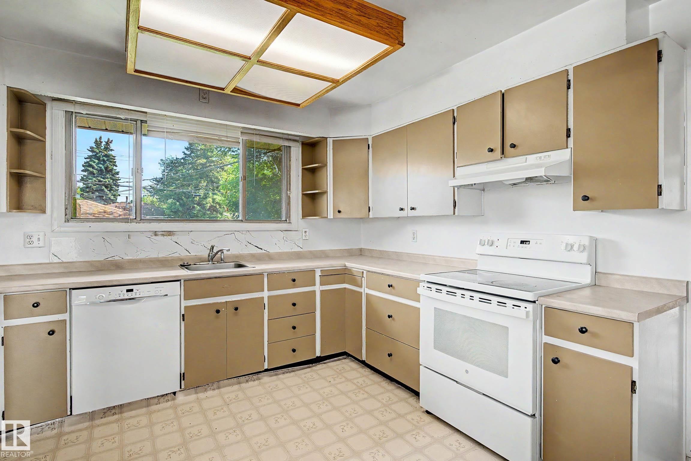 Kitchen featuring a built-in dishwasher, white electric range, and ample cabinetry with contrasting finishes - 9723 76 Street Nw, Edmonton, AB - Indoor Photo Showing Kitchen