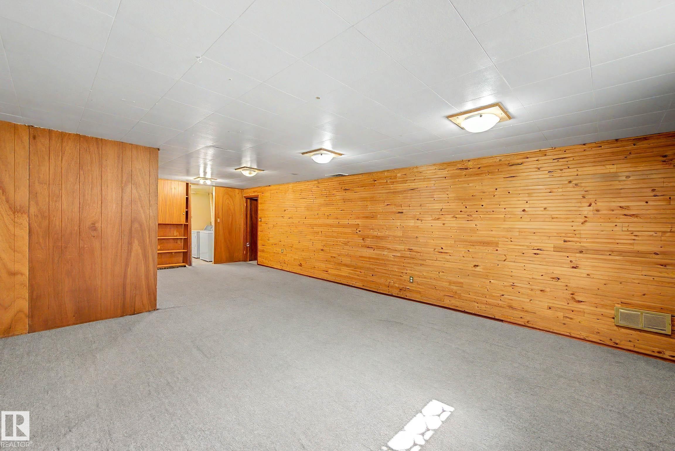 Expansive room with carpet flooring, wood paneling, and built-in shelving - 9723 76 Street Nw, Edmonton, AB - Indoor Photo Showing Other Room