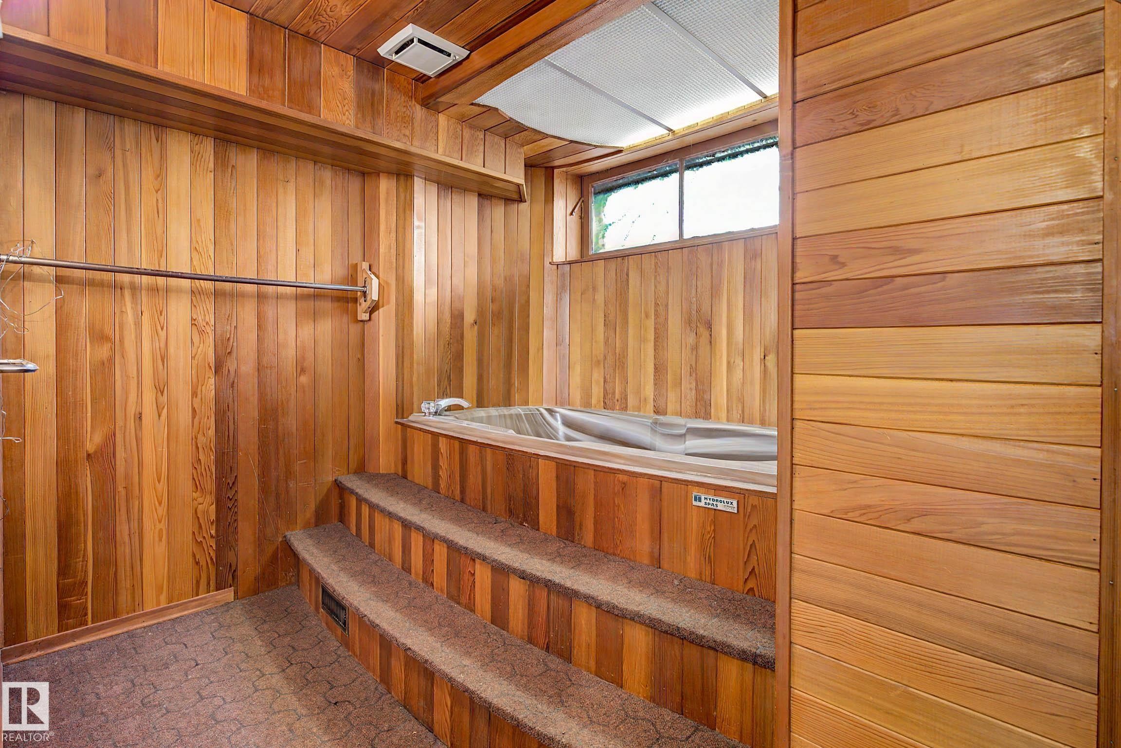 Wood-paneled room with an integrated hot tub, multi-tiered steps with carpeted treads, and a transom window - 9723 76 Street Nw, Edmonton, AB - Indoor Photo Showing Other Room