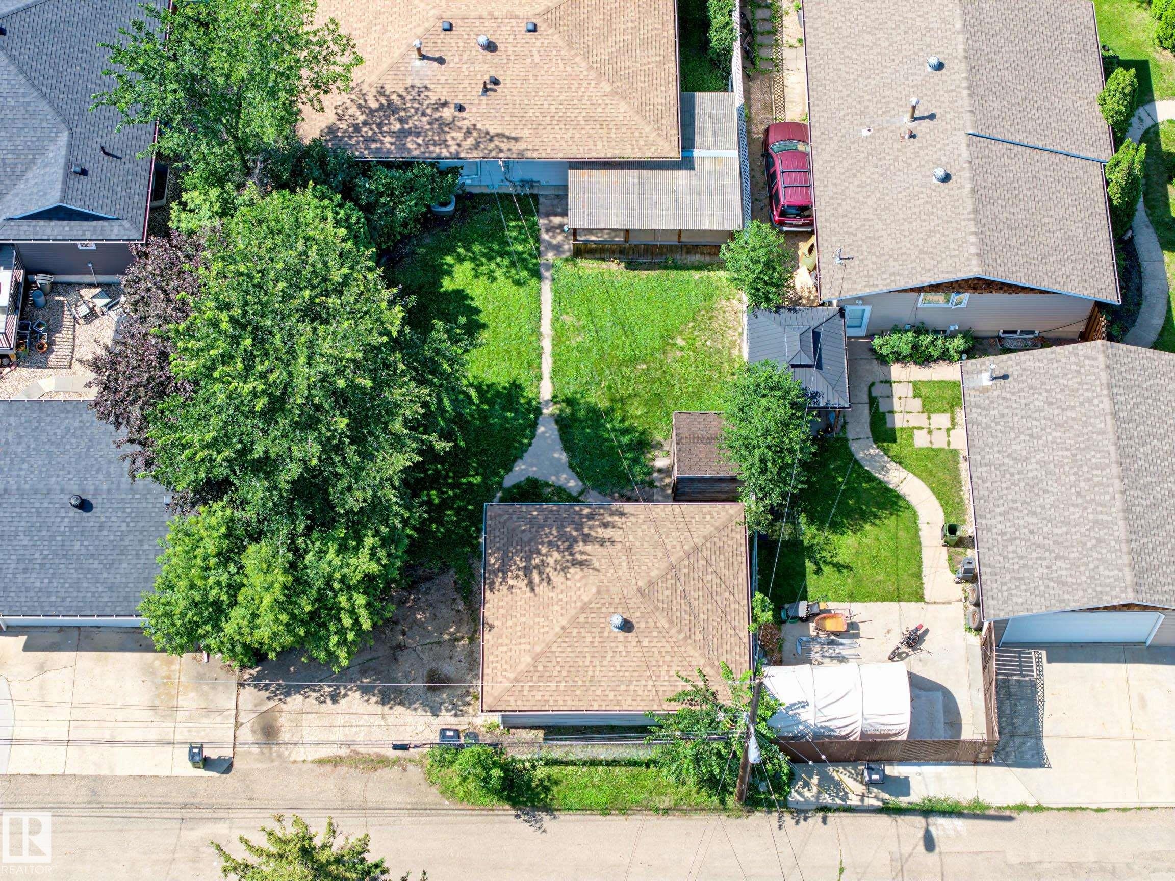 Expansive backyard featuring a manicured lawn, established trees, and concrete pathways - 9723 76 Street Nw, Edmonton, AB - Outdoor