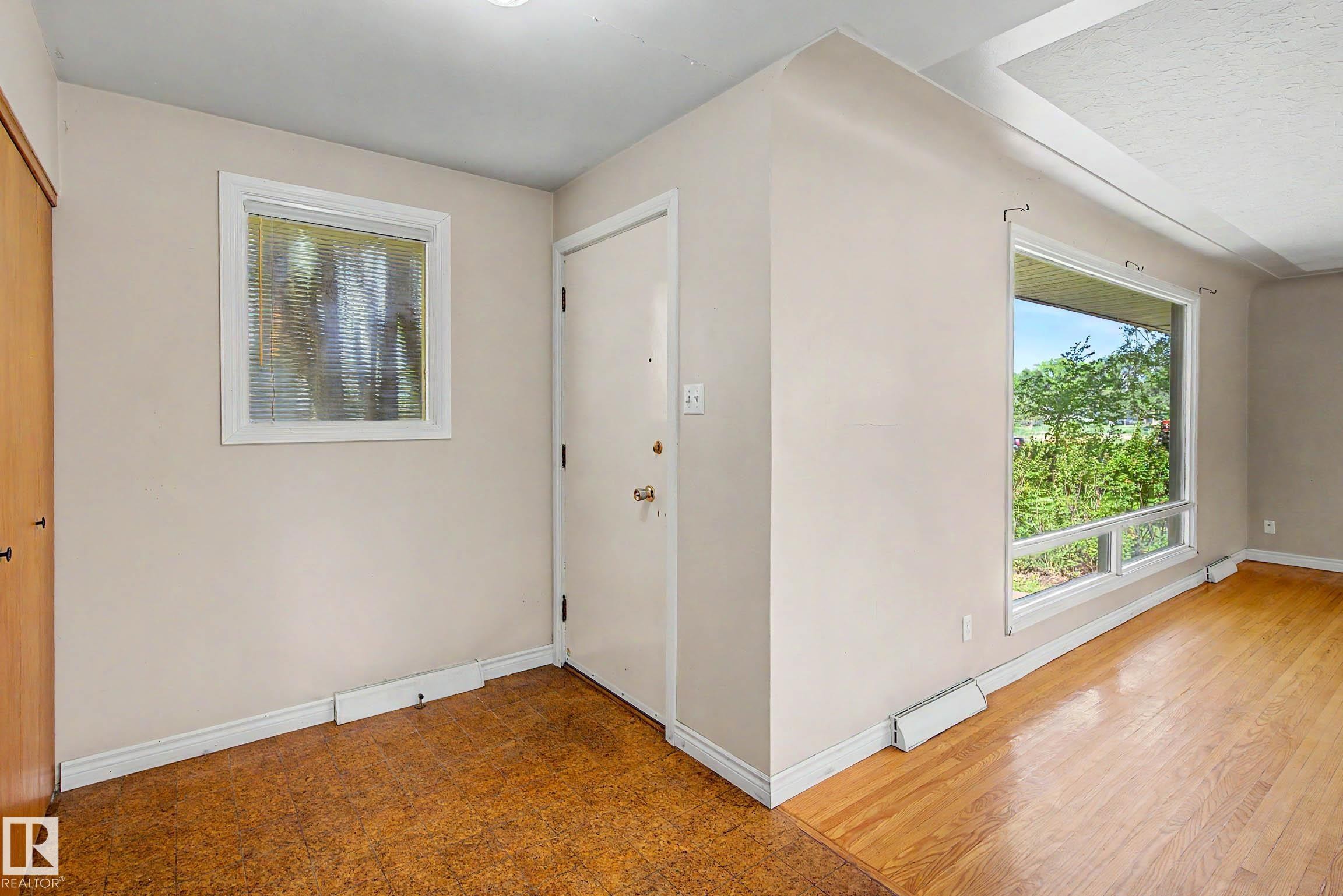 Hardwood flooring, front entry door, textured glass window, and large picture window - 9723 76 Street Nw, Edmonton, AB - Indoor Photo Showing Other Room