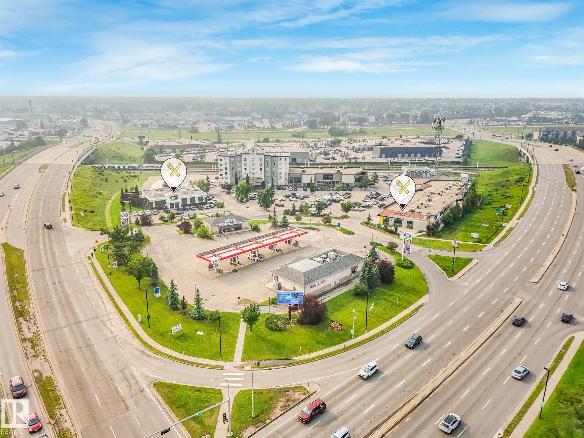 Aerial view featuring a commercial complex with multiple buildings, surface parking areas, and adjacent multi-lane roadways - 4135 134 Avenue Nw, Edmonton, AB - Outdoor With View