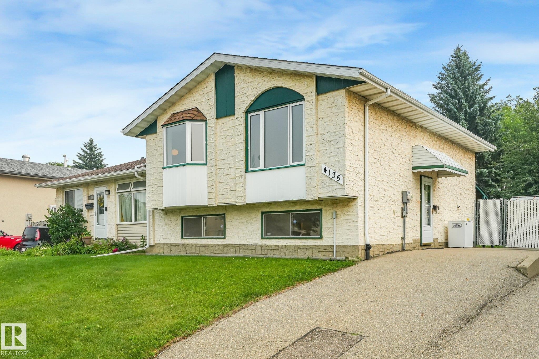 Split-level residence featuring a textured stucco exterior with green trim accents and a partial stone facade - 4135 134 Avenue Nw, Edmonton, AB - Outdoor