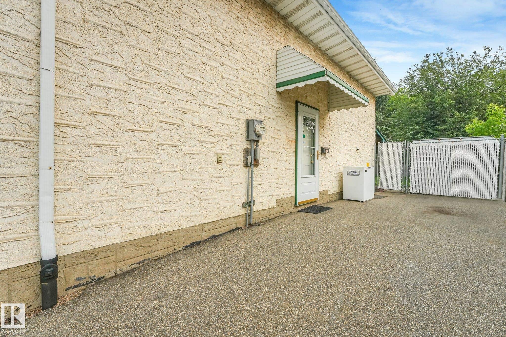 Textured stucco exterior with a decorative green and white awning over a glass-paneled door - 4135 134 Avenue Nw, Edmonton, AB - Outdoor With Exterior