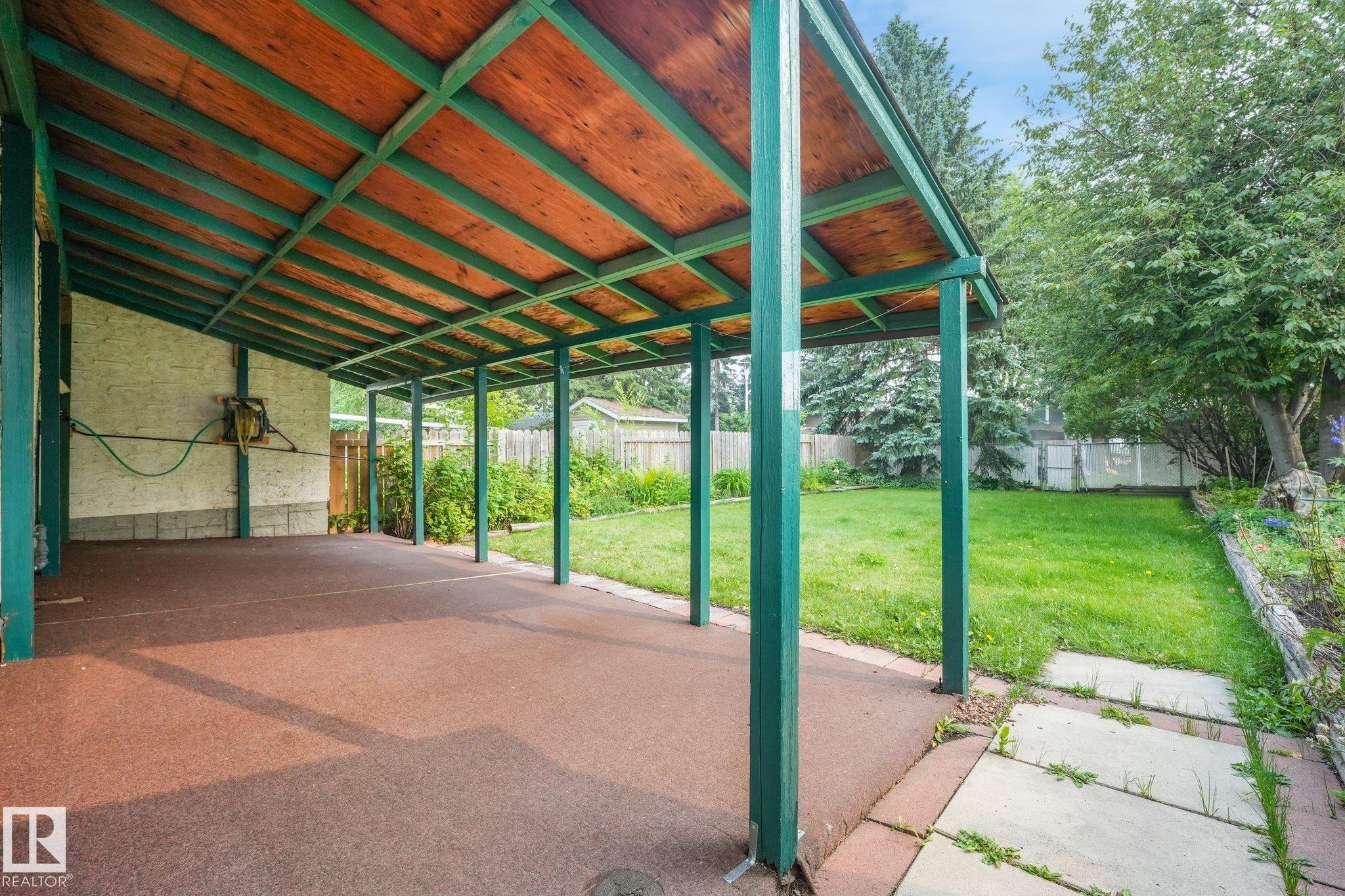 Spacious covered patio area with a wood-finish ceiling and painted support beams - 4135 134 Avenue Nw, Edmonton, AB - Outdoor With Exterior