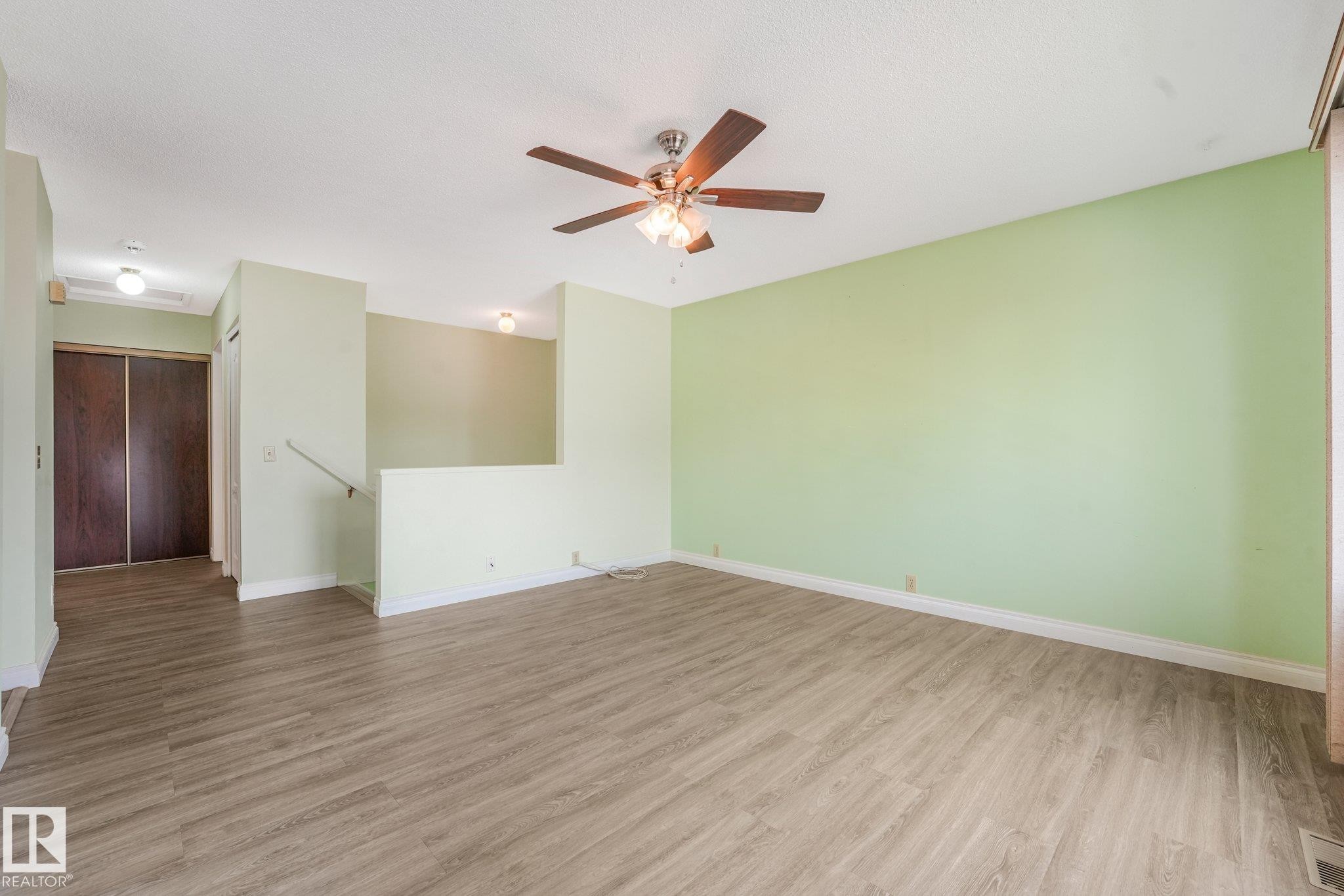Spacious living area featuring wood-finish flooring, a ceiling fan, and light green walls - 4135 134 Avenue Nw, Edmonton, AB - Indoor Photo Showing Other Room