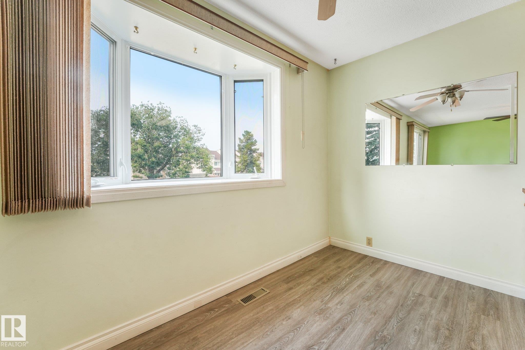 Bay window offering neighborhood views, wood-finish flooring, ceiling fan, and light green wall finish - 4135 134 Avenue Nw, Edmonton, AB - Indoor Photo Showing Other Room