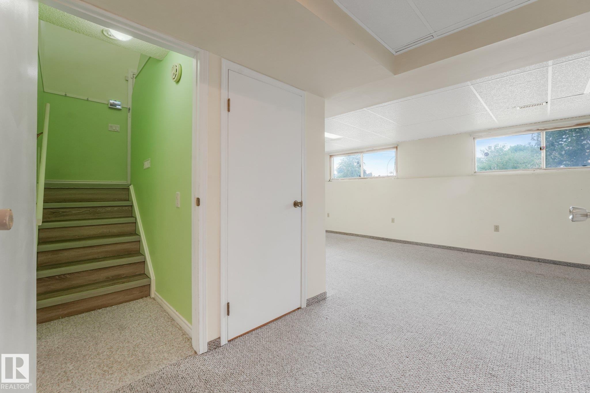 Spacious lower-level room featuring light gray carpet flooring and two windows, providing natural illumination - 4135 134 Avenue Nw, Edmonton, AB - Indoor