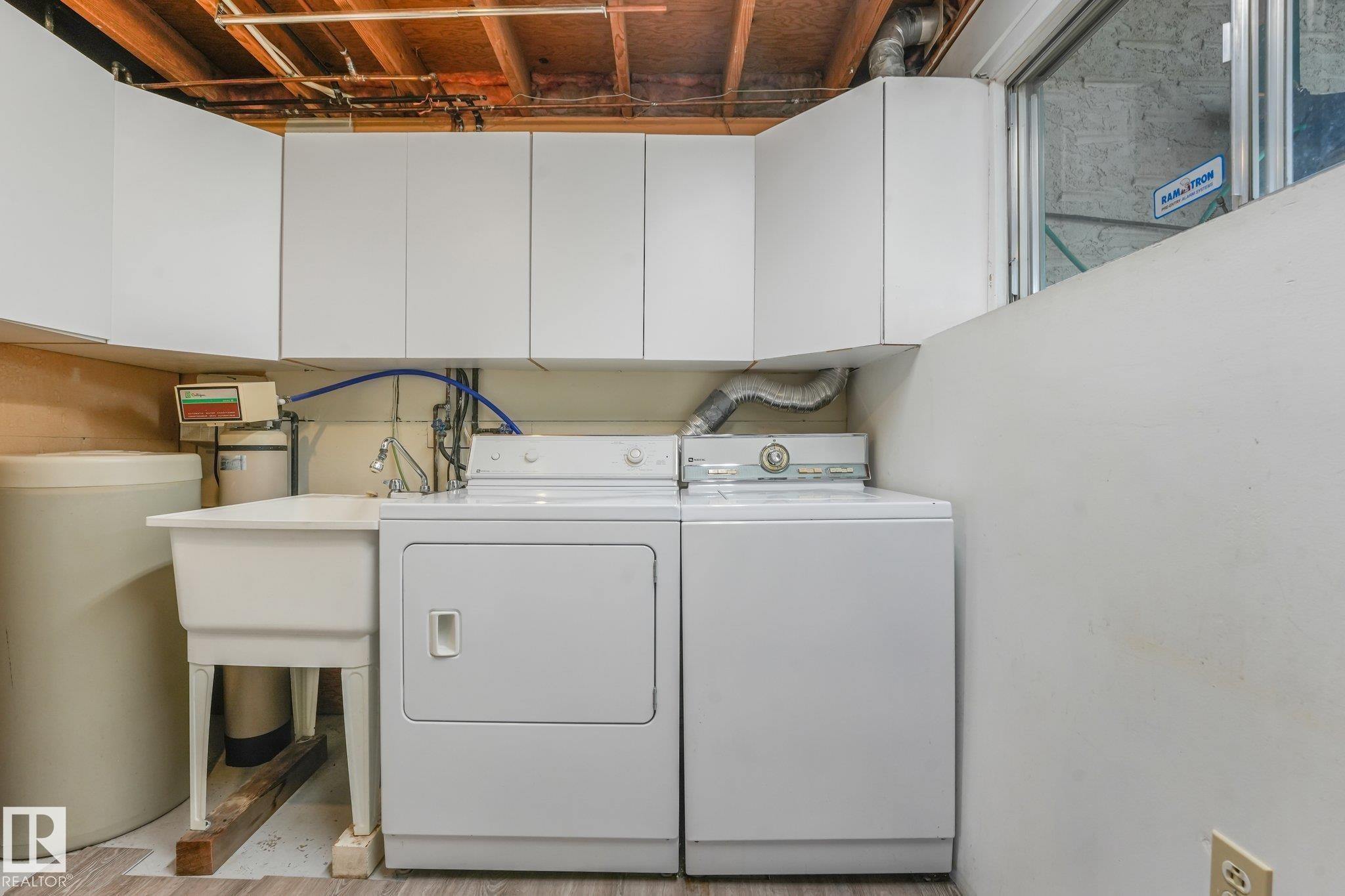 Laundry area featuring white cabinetry, a utility sink, and wood-finish flooring - 4135 134 Avenue Nw, Edmonton, AB - Indoor Photo Showing Laundry Room