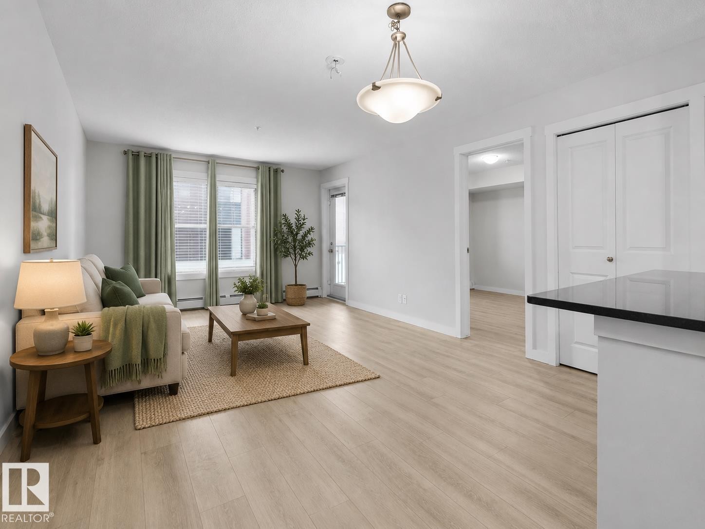 Recessed lighting, wood-finish flooring, white trim, and a white interior door with dark hardware - #205 5816 Mullen Pl Nw, Edmonton, AB - Indoor Photo Showing Living Room