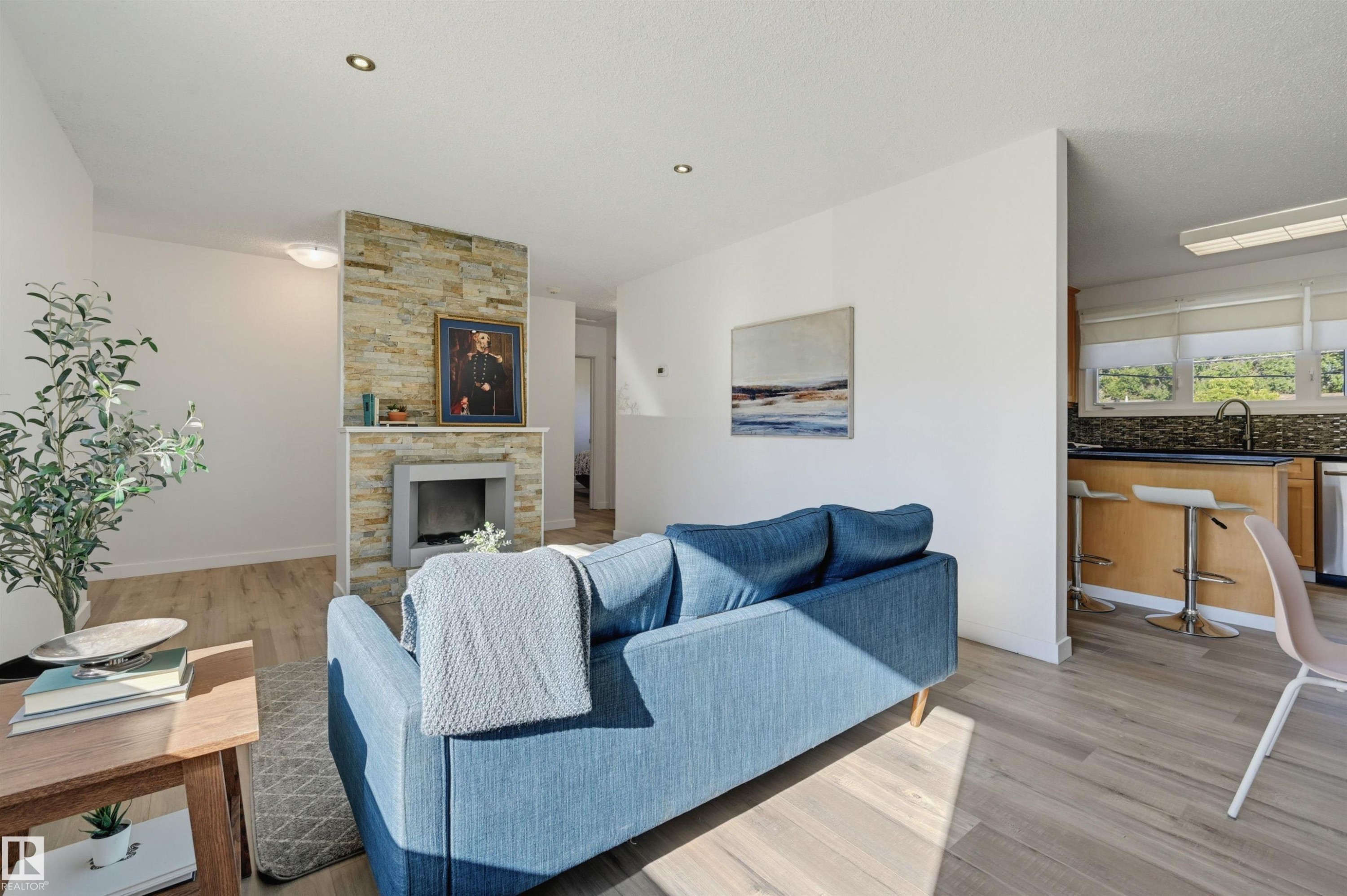 Wood-finish flooring, recessed lighting, and a stacked stone fireplace with a built-in hearth - 9127 149 Street Nw, Edmonton, AB - Indoor Photo Showing Living Room With Fireplace