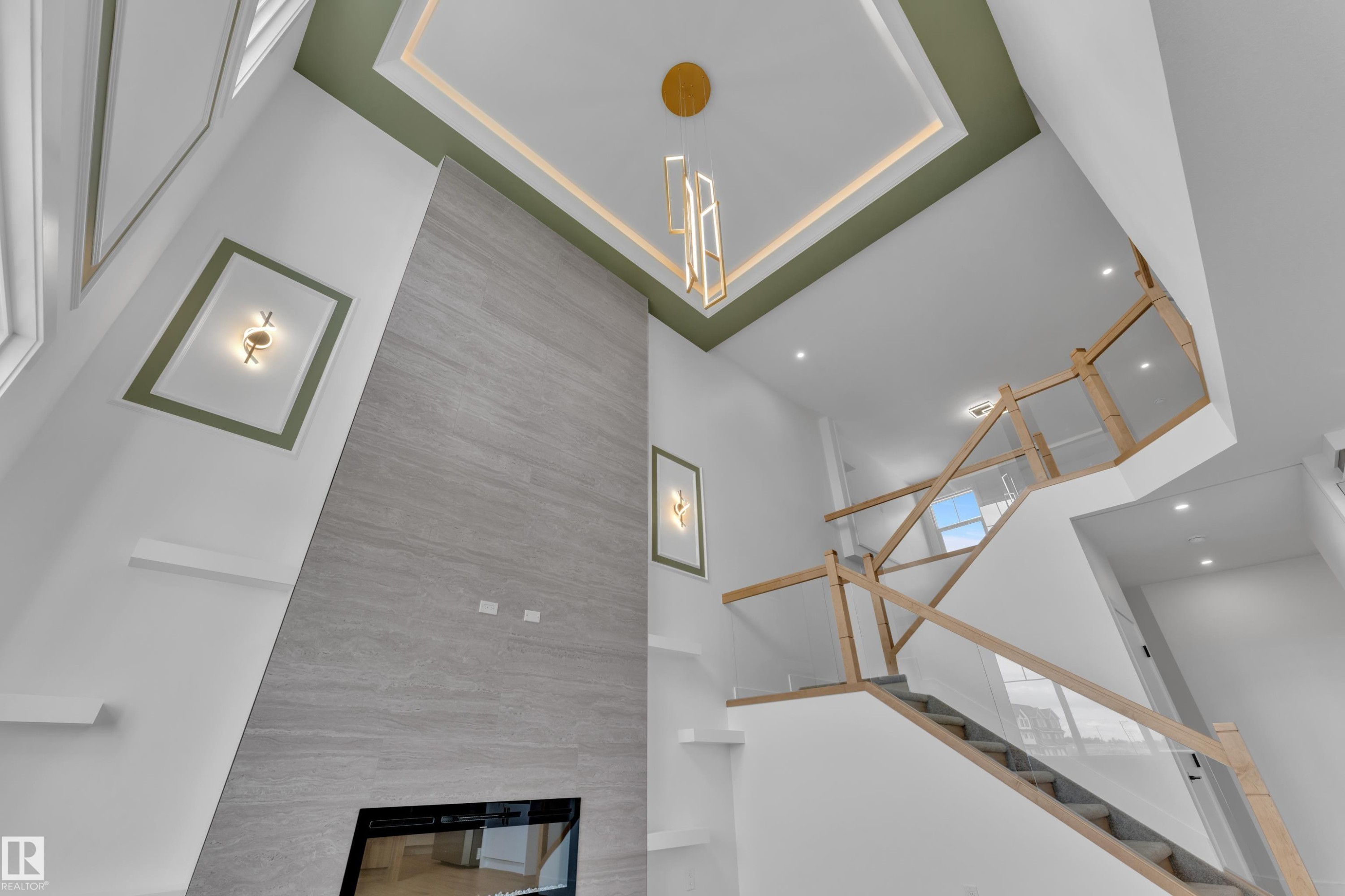 Two-story living area with a built-in linear fireplace, a floor-to-ceiling accent wall, and a custom staircase with glass panels - 764 Astoria Way, Devon, AB - Indoor Photo Showing Other Room