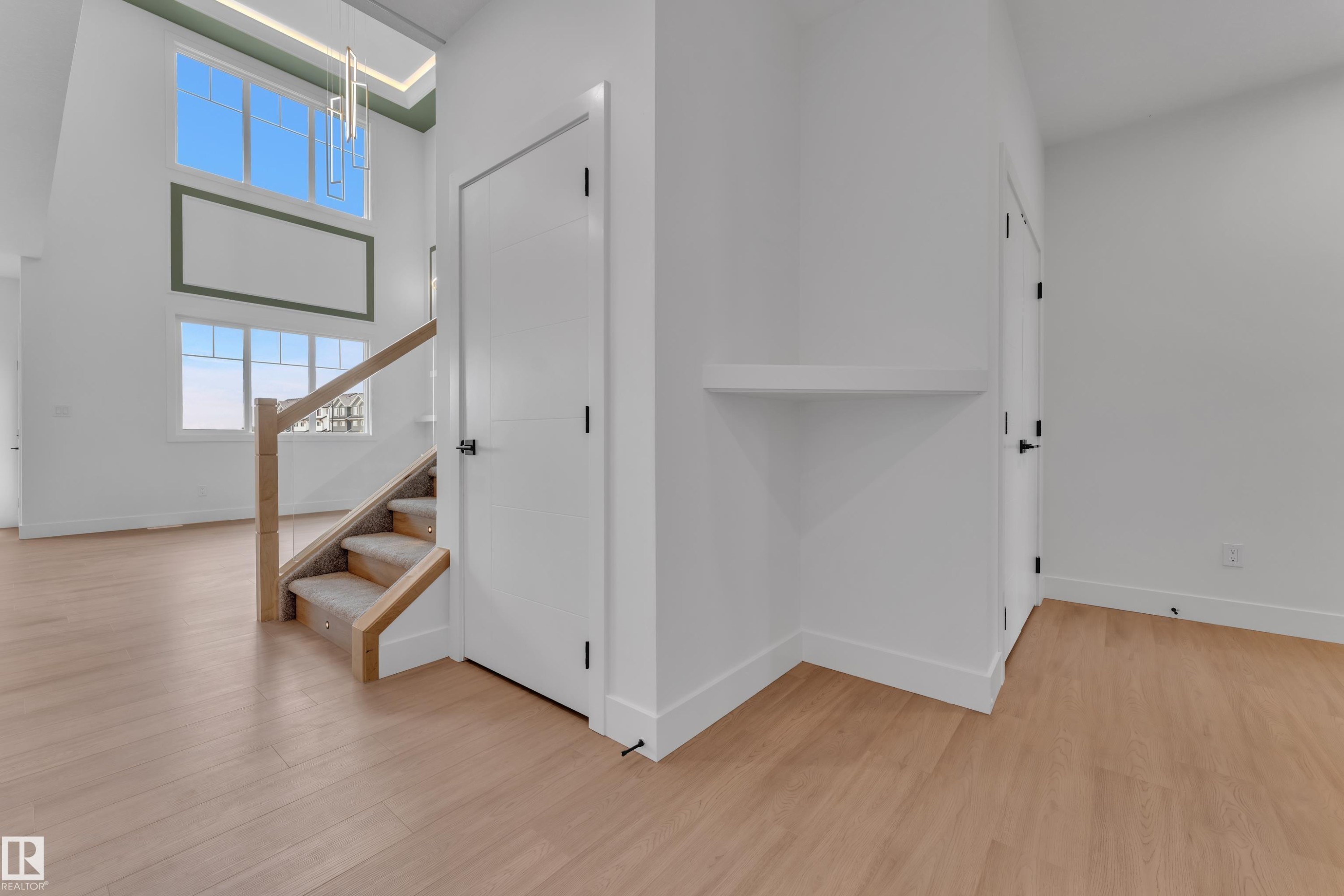 Tall ceilings with a contemporary chandelier, large windows with natural light, wood-finish flooring, a staircase with carpeting, and white interior doors - 764 Astoria Way, Devon, AB - Indoor Photo Showing Other Room