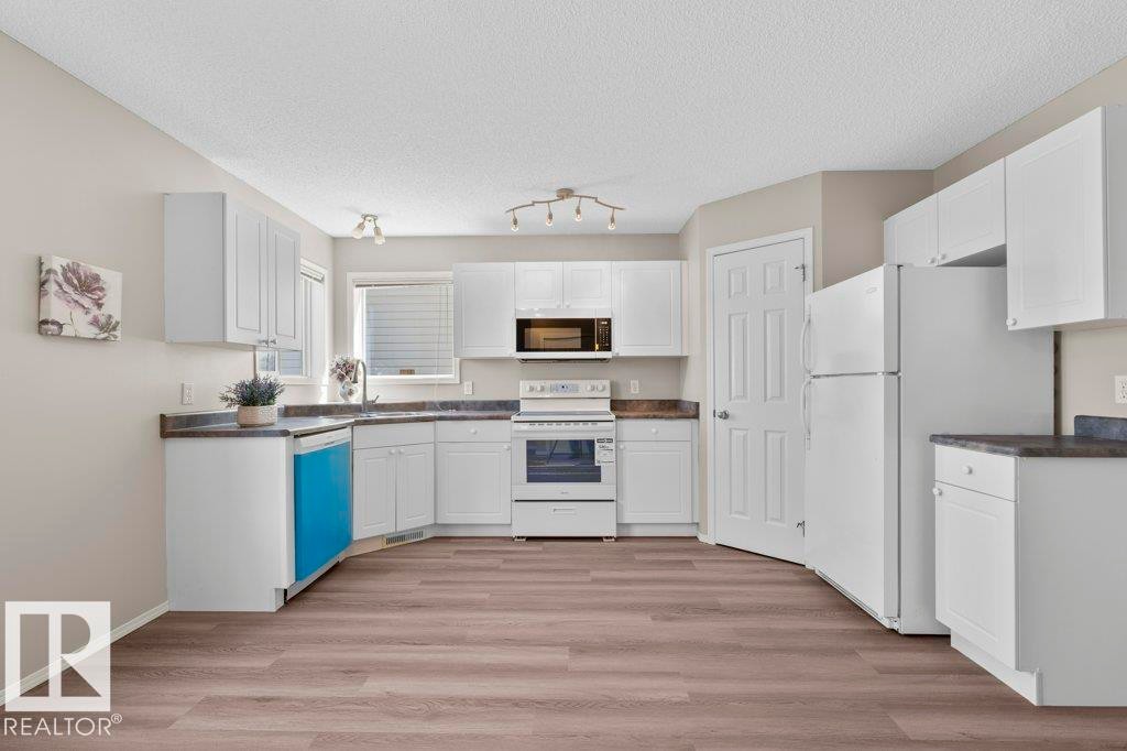 U-shaped kitchen featuring white cabinetry, dark countertops, and wood-finish flooring - 21344 88 Avenue Nw, Edmonton, AB - Indoor Photo Showing Kitchen