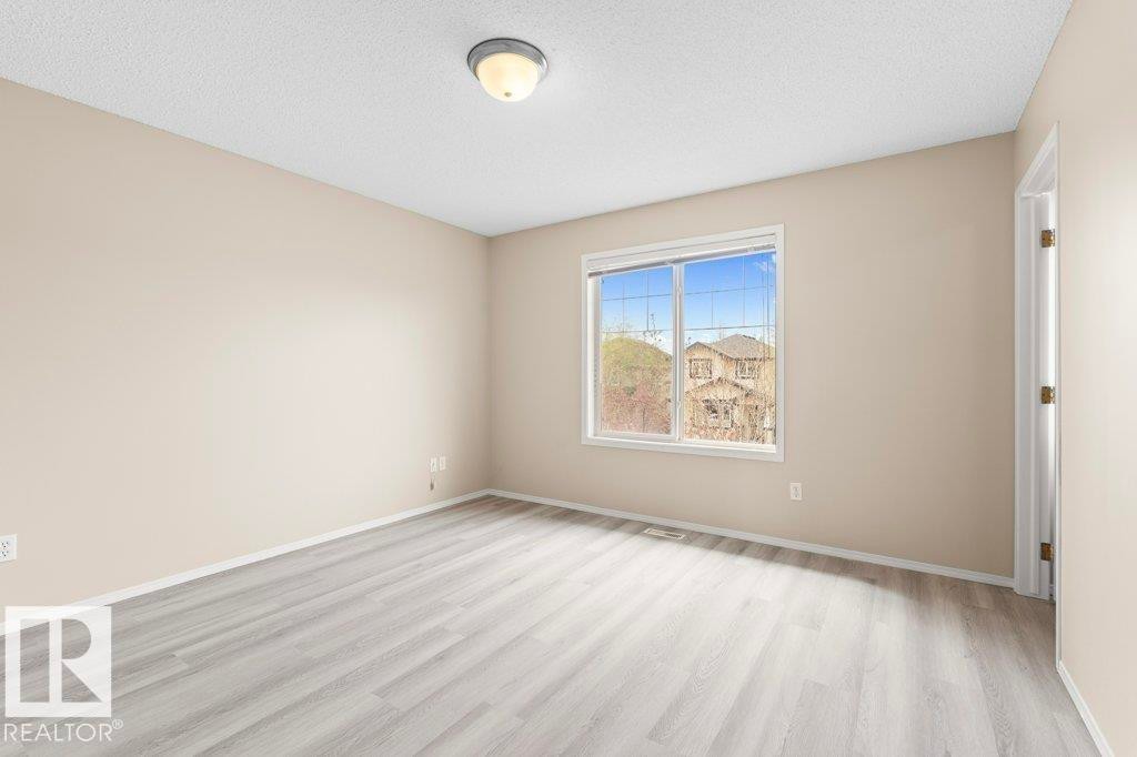 Room featuring wood-finish flooring, neutral wall tones, white trim, and a window with grid patterns - 21344 88 Avenue Nw, Edmonton, AB - Indoor Photo Showing Other Room