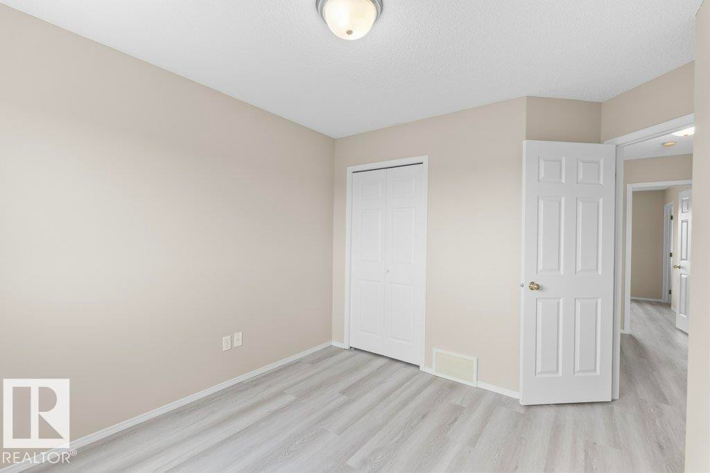 Light wood-finish flooring complements the neutral wall color and white trim - 21344 88 Avenue Nw, Edmonton, AB - Indoor Photo Showing Other Room