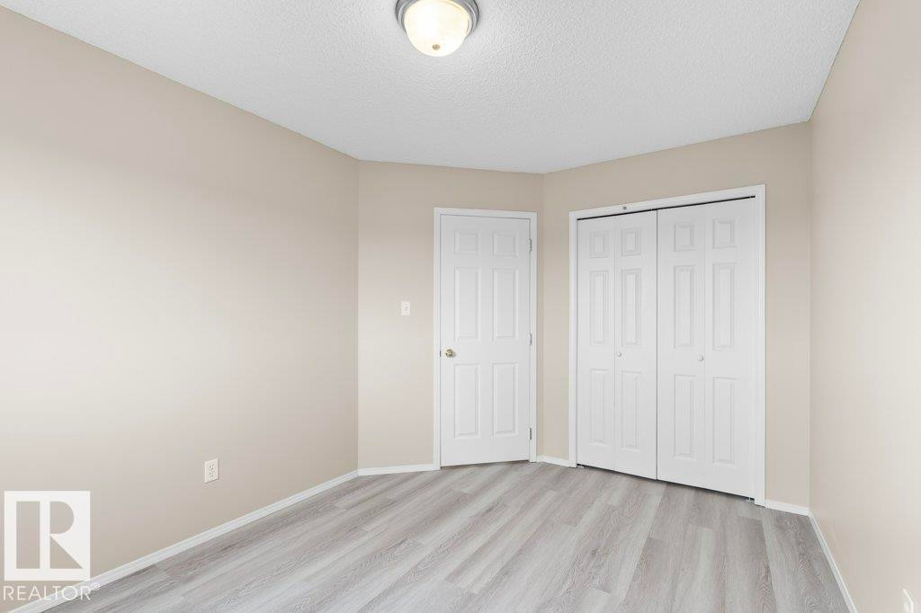 Room featuring wood-finish flooring, neutral wall paint, white trim, and a ceiling-mounted light fixture - 21344 88 Avenue Nw, Edmonton, AB - Indoor
