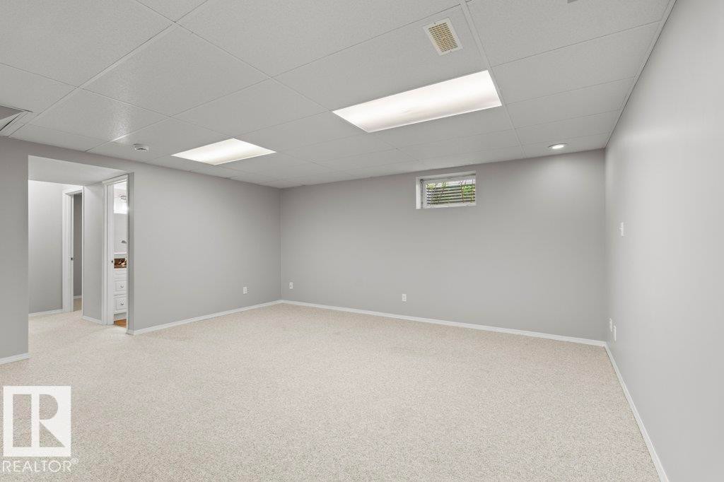 Spacious room featuring light-colored carpeting, neutral painted walls, and a drop ceiling with recessed lighting - 21344 88 Avenue Nw, Edmonton, AB - Indoor Photo Showing Basement