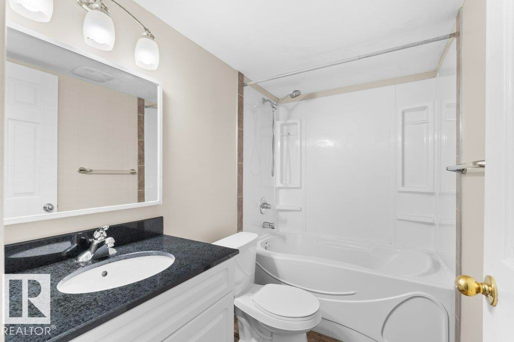 Full bathroom featuring a white vanity with dark speckled countertop, undermount sink, and polished chrome faucet - 21344 88 Avenue Nw, Edmonton, AB - Indoor Photo Showing Bathroom