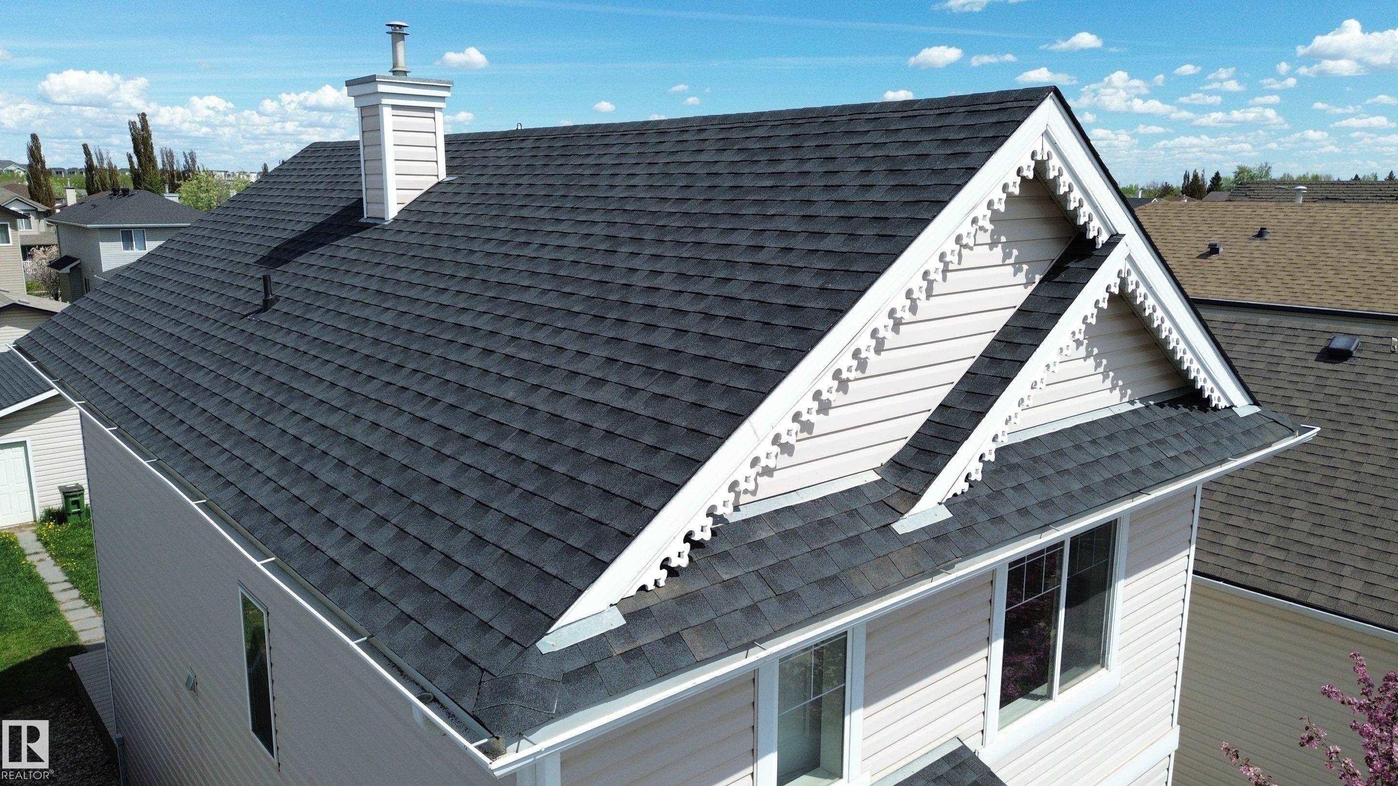 House exterior with dark asphalt shingle roofing, light-colored siding, decorative white trim, and a white chimney - 21344 88 Avenue Nw, Edmonton, AB - Outdoor