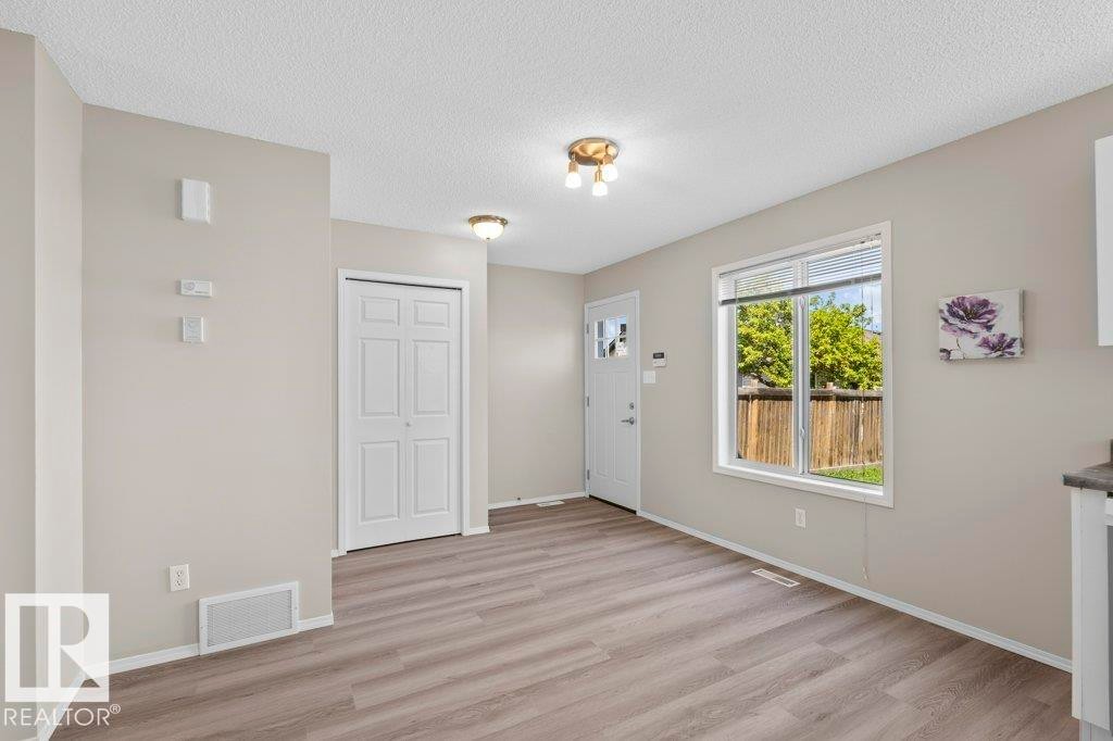Entryway featuring wood-finish flooring, a white front door with decorative glass, and a large window overlooking a wooden privacy fence - 21344 88 Avenue Nw, Edmonton, AB - Indoor Photo Showing Other Room