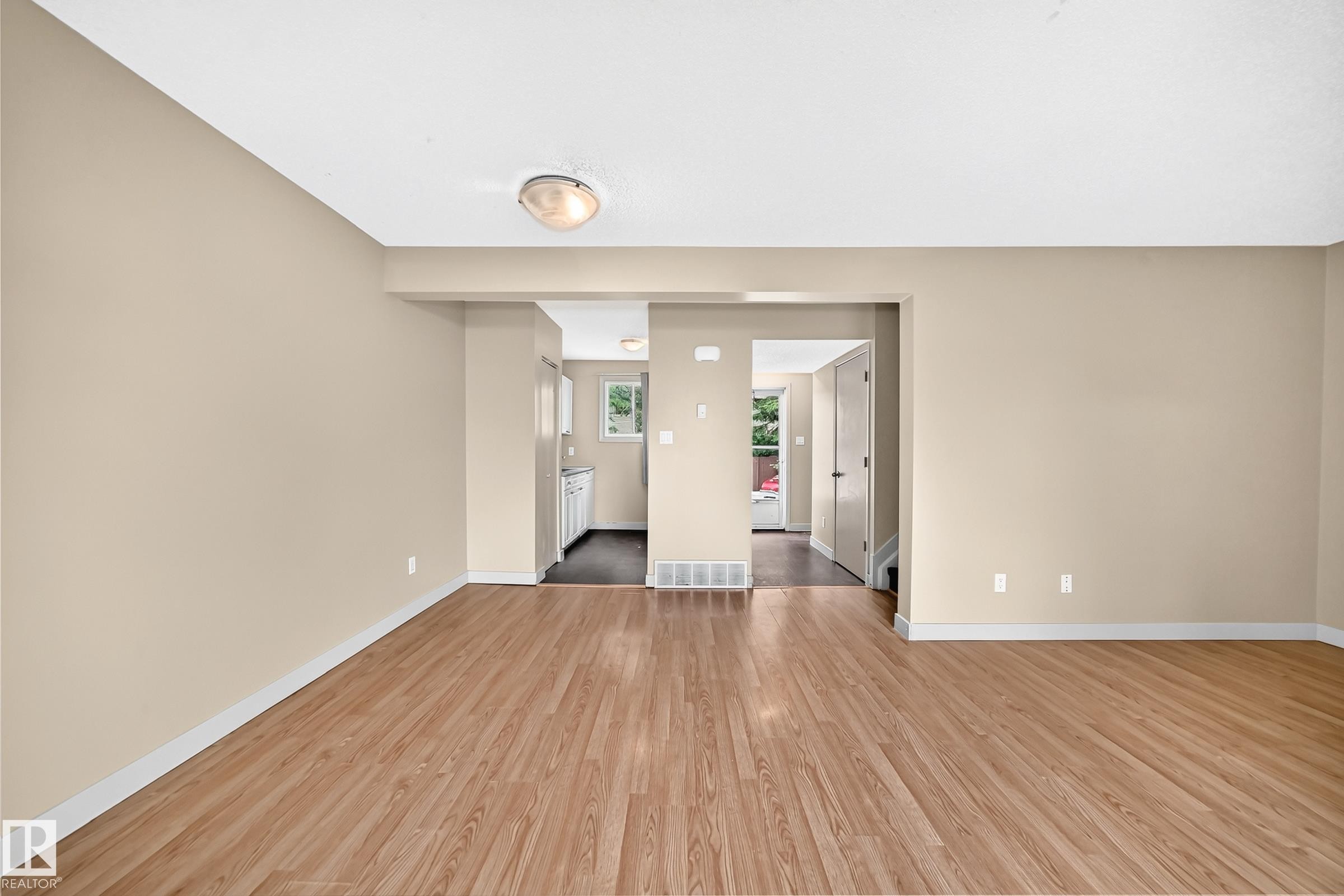 Wood-finish flooring throughout, neutral paint colors, and a ceiling-mounted light fixture - 6416 180 Street Nw, Edmonton, AB - Indoor Photo Showing Other Room