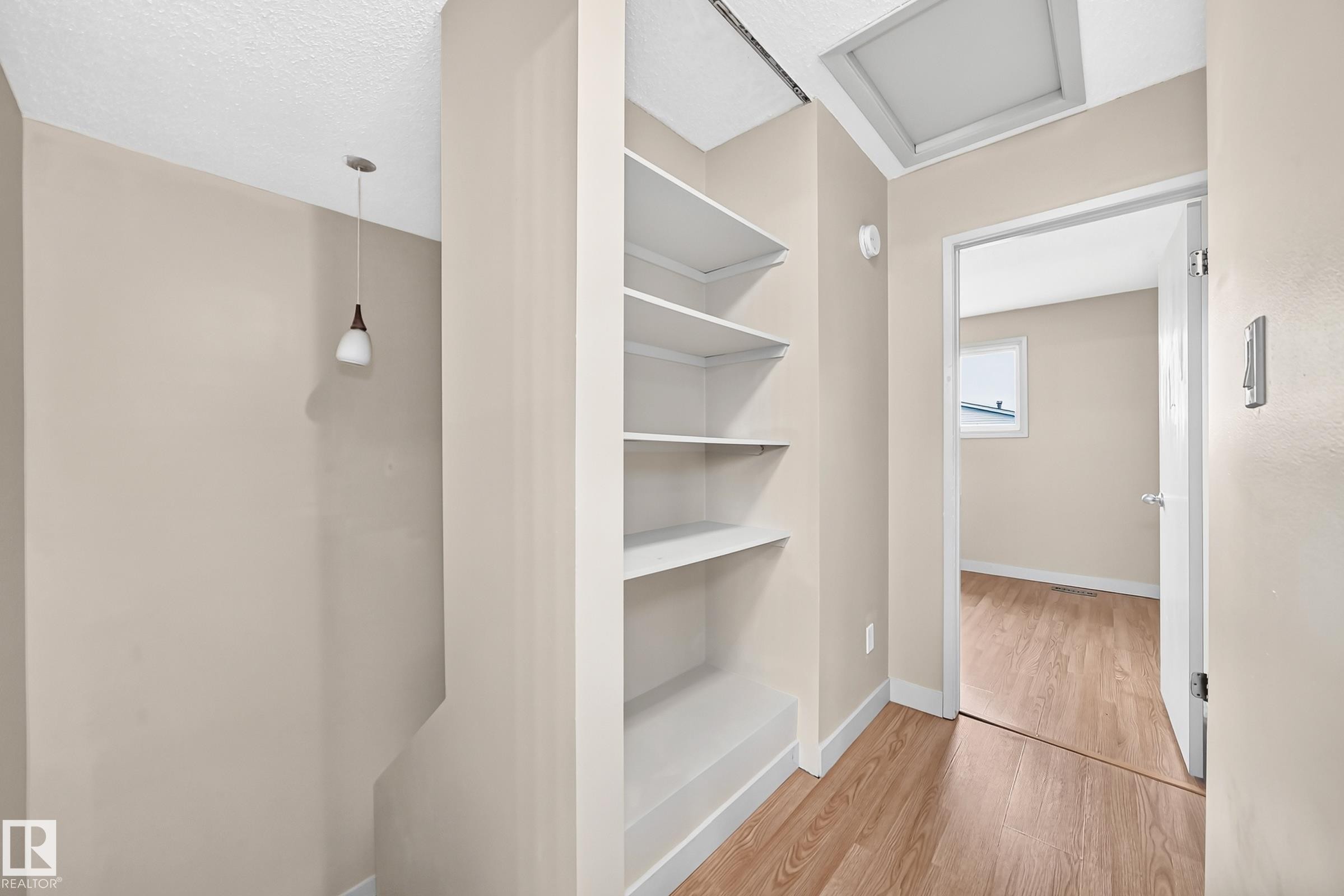 Built-in shelving, wood-finish flooring, recessed lighting, and a suspended pendant light fixture - 6416 180 Street Nw, Edmonton, AB - Indoor