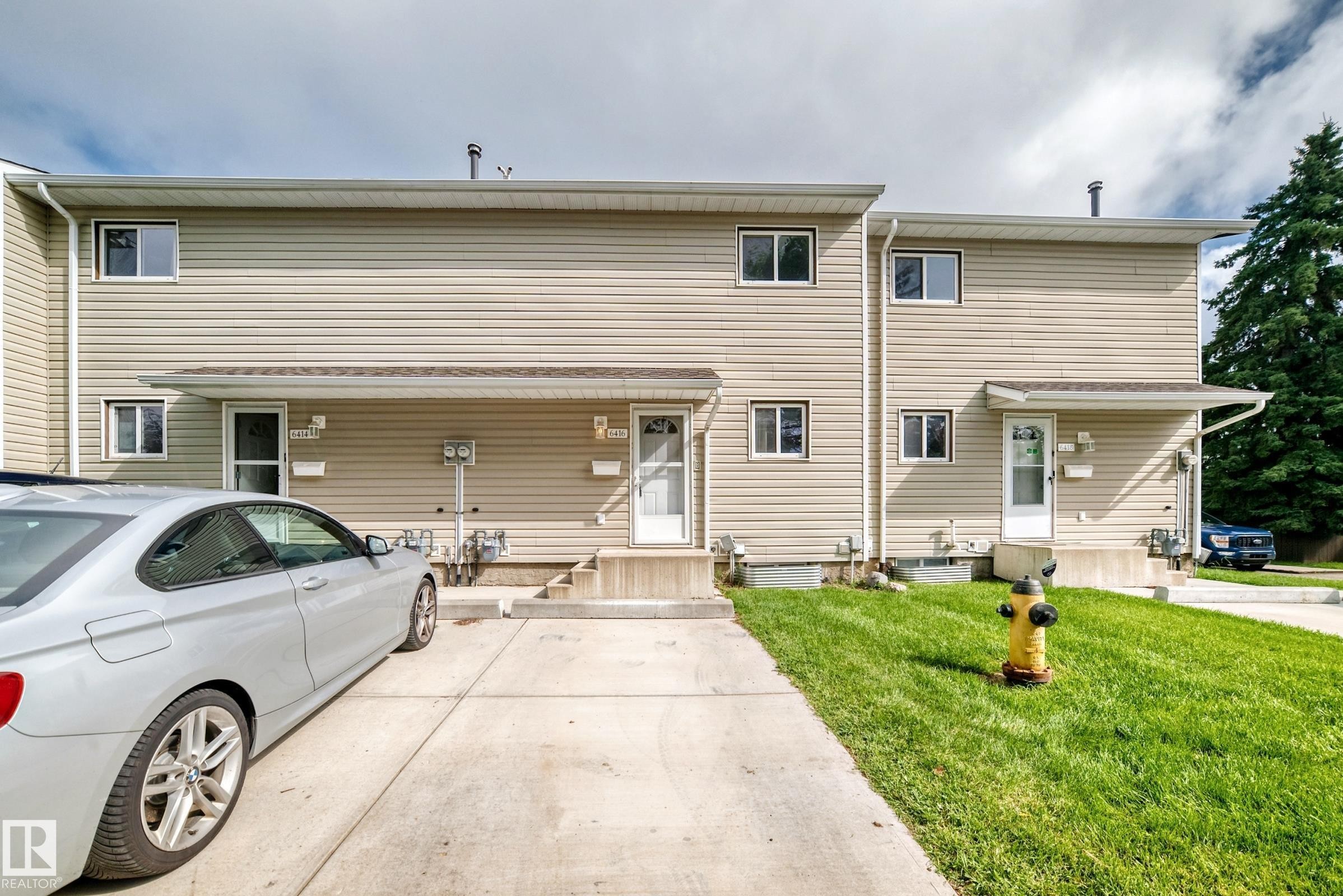 Vinyl siding exterior with multiple windows, concrete walkways, and a manicured lawn - 6416 180 Street Nw, Edmonton, AB - Outdoor