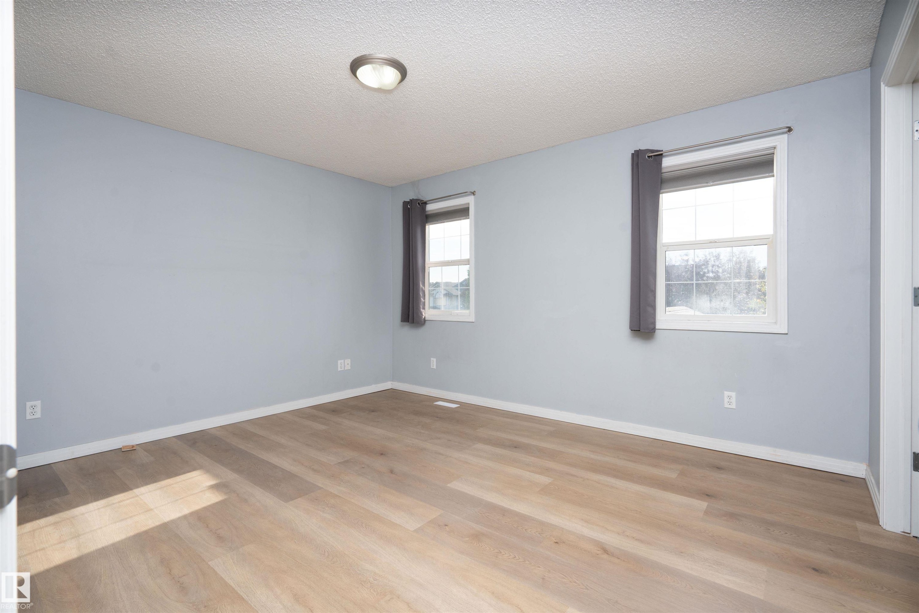 Wood-finish flooring, two windows with white trim, and a ceiling-mounted light fixture - 1009 Macewan Close Sw, Edmonton, AB - Indoor Photo Showing Other Room