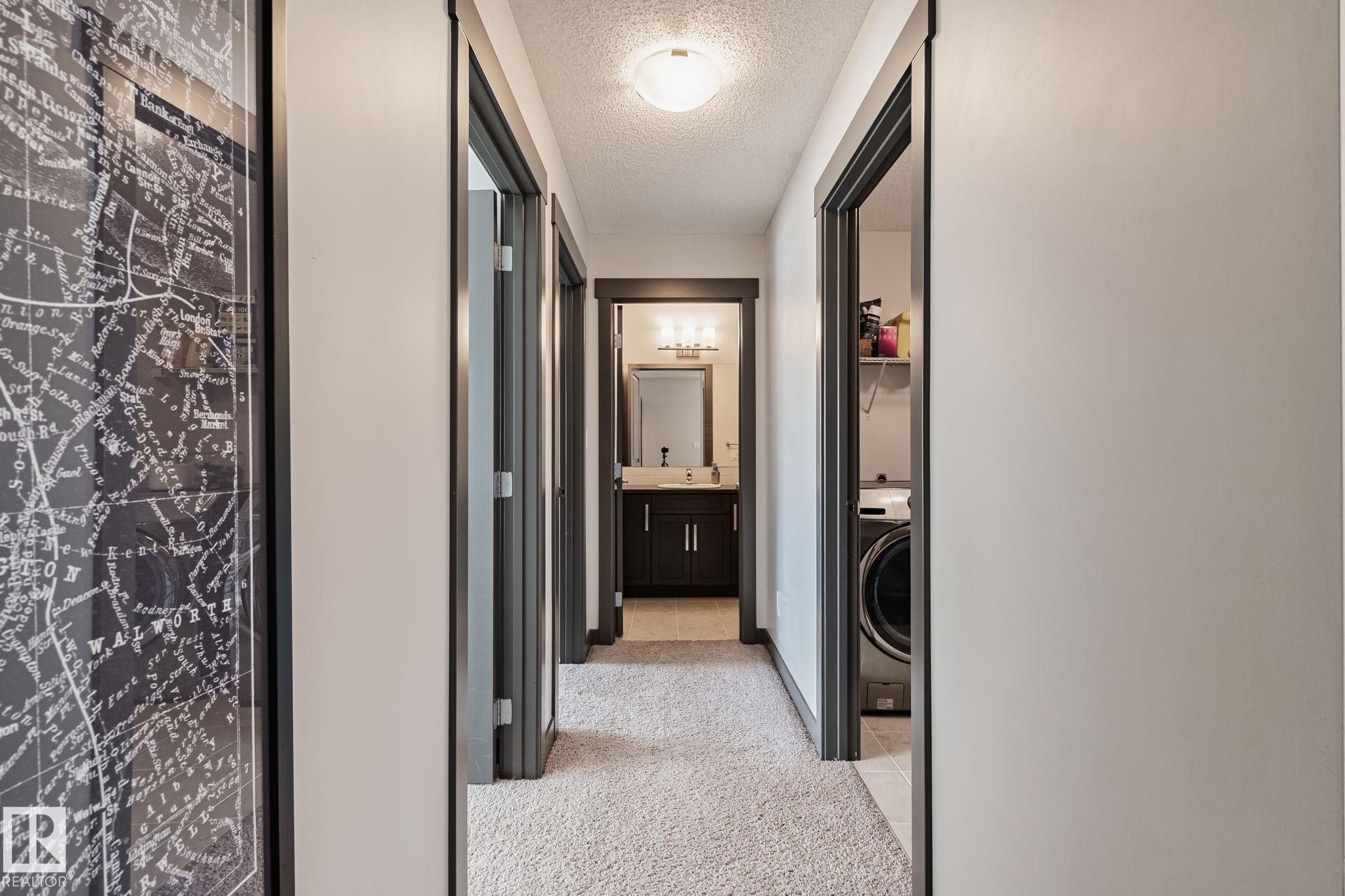 Hallway featuring carpet flooring, multiple doorways, and a flush mount ceiling light - 1337 Secord Landing Nw, Edmonton, AB - Indoor