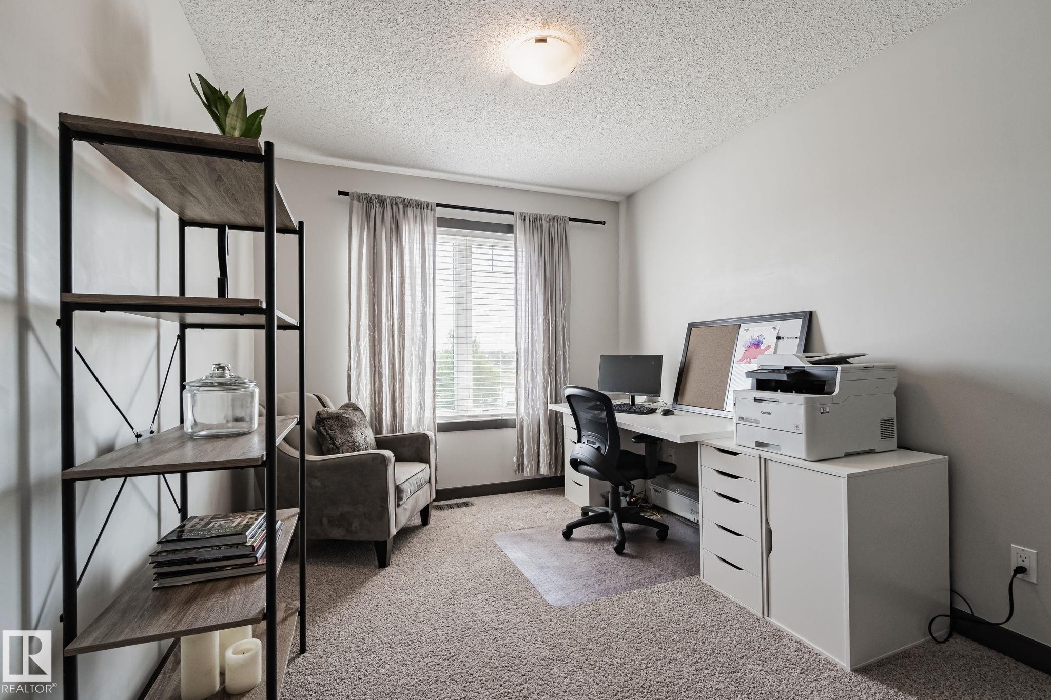 Recessed window with blinds and drapes, wall-to-wall carpeting, and a ceiling-mounted light fixture - 1337 Secord Landing Nw, Edmonton, AB - Indoor Photo Showing Office