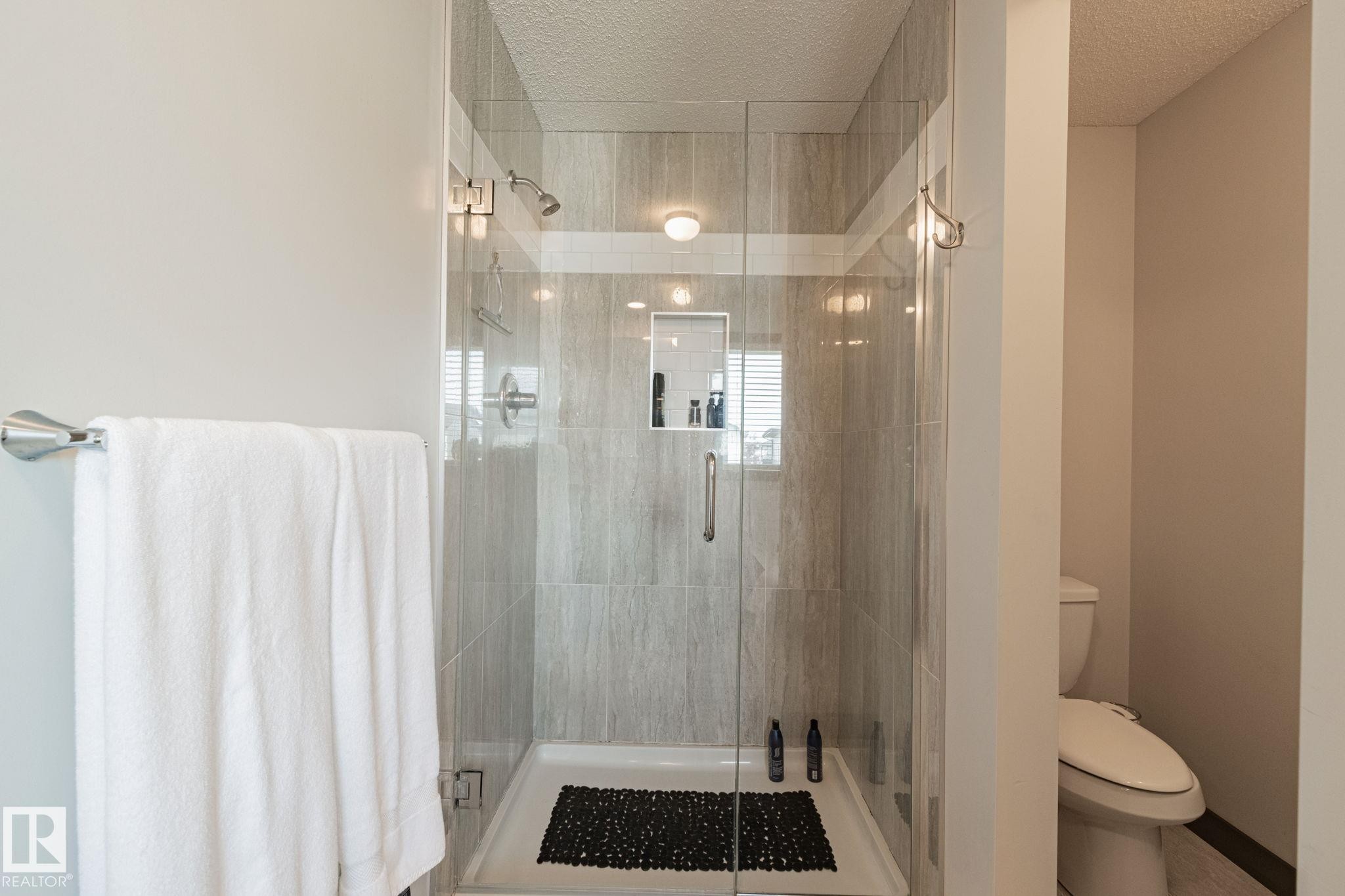 Glass-enclosed shower with a tiled interior and recessed niche - 1337 Secord Landing Nw, Edmonton, AB - Indoor Photo Showing Bathroom