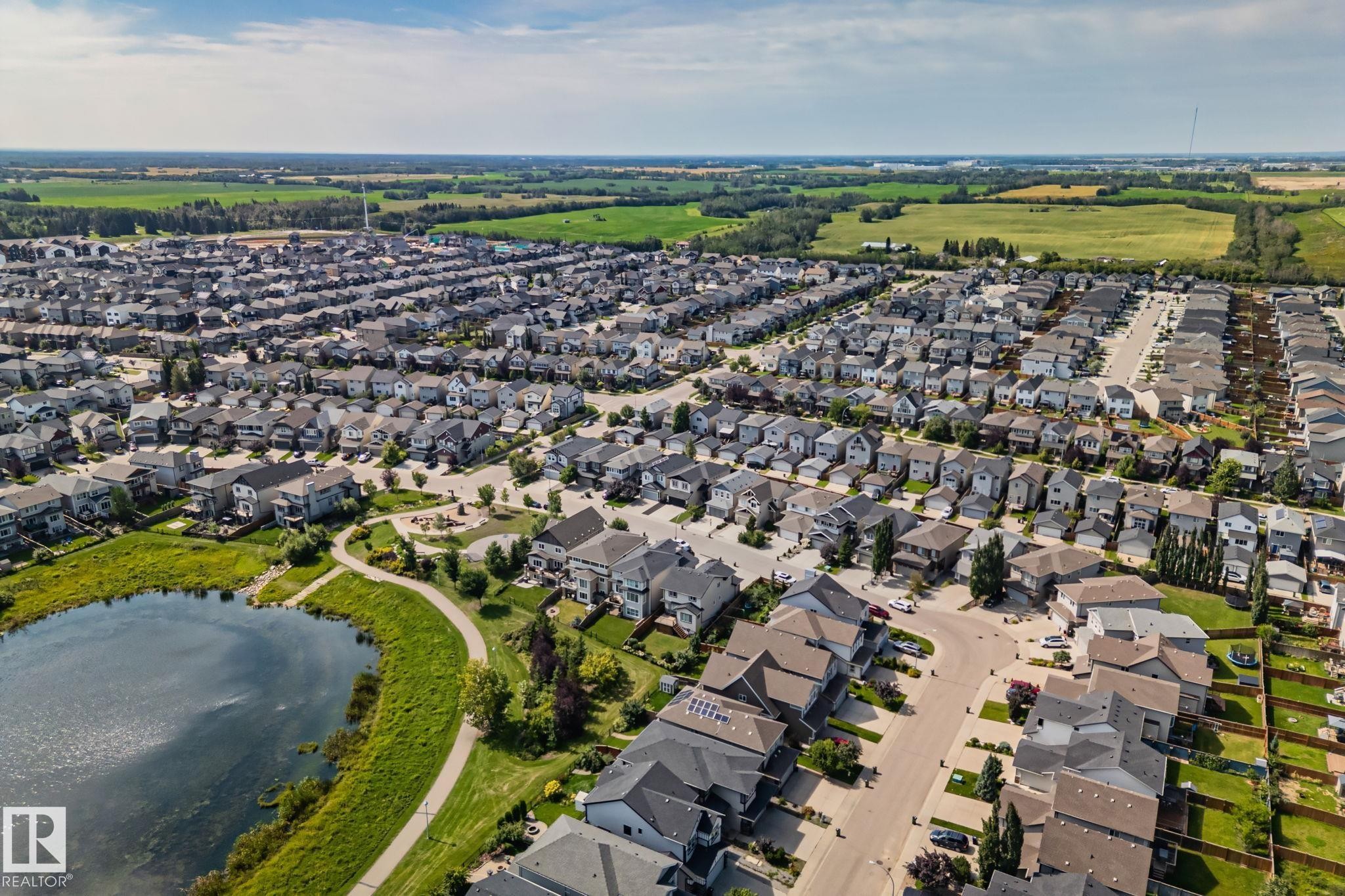 Residential community with a large central pond, curvilinear pathways, and adjacent green spaces - 1337 Secord Landing Nw, Edmonton, AB - Outdoor With View